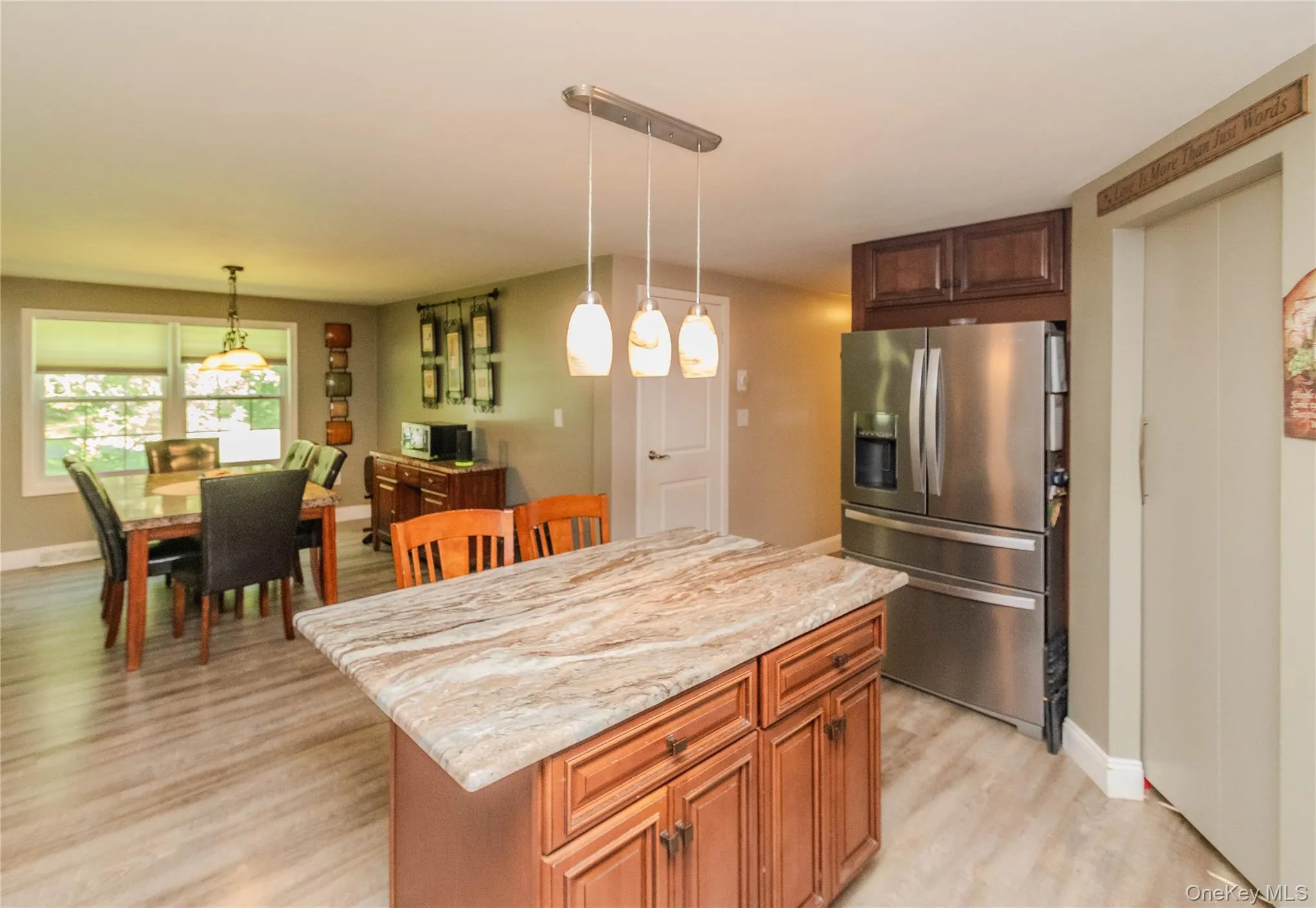 Kitchen island with a light-toned stone countertop, wood cabinetry, and pendant lighting Kitchen island with a light-toned stone countertop, wood cabinetry, and pendant lighting