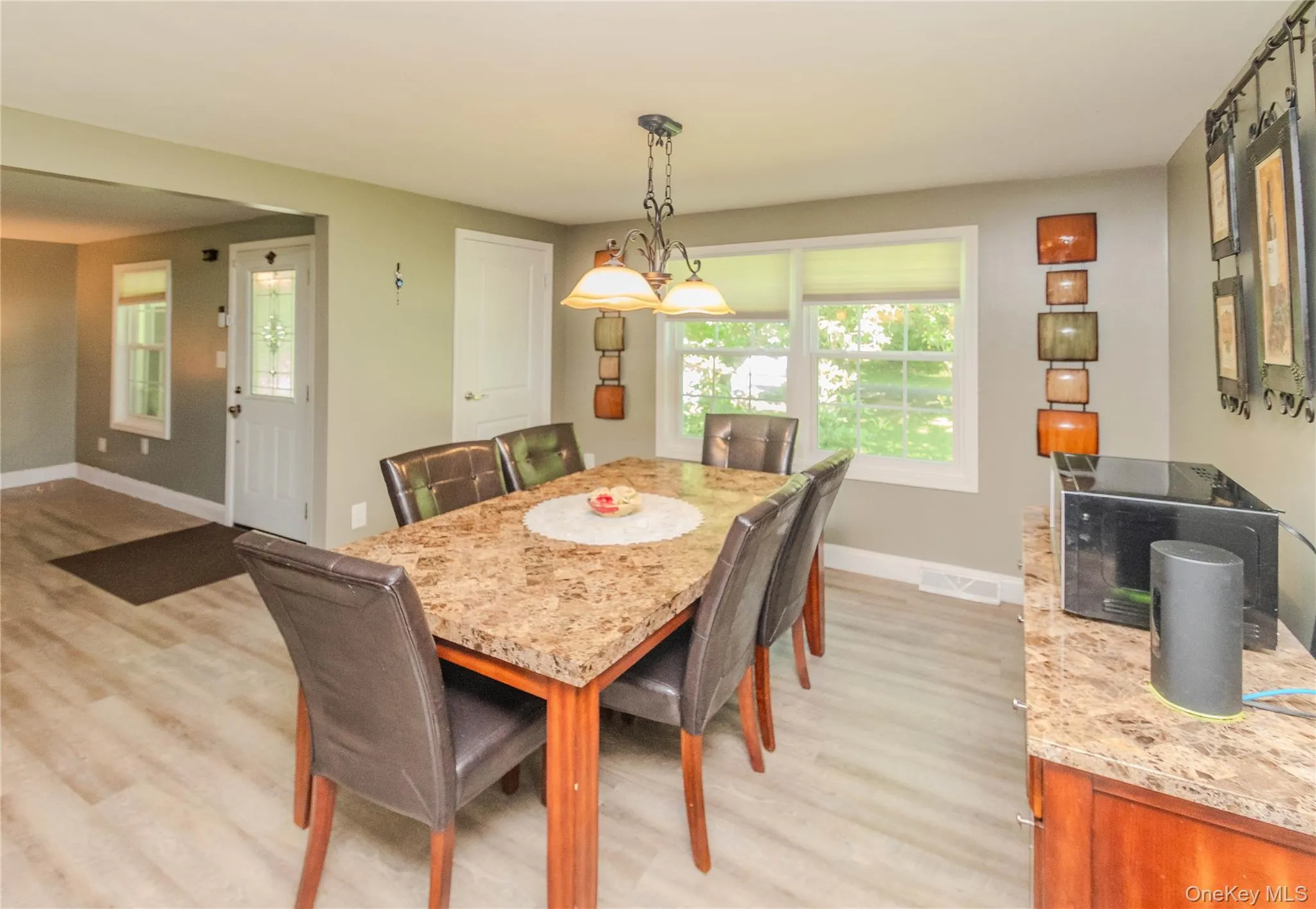 Dining area featuring wood-finish flooring, a contemporary chandelier, and a built-in buffet with a stone-finish countertop Dining area featuring wood-finish flooring, a contemporary chandelier, and a built-in buffet with a stone-finish countertop