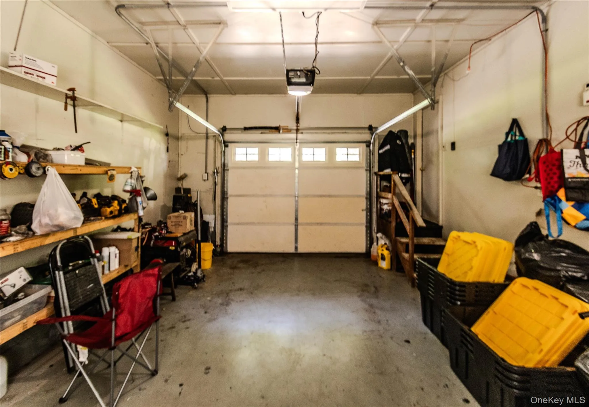 Two-car garage featuring a paneled overhead door with upper window inserts, concrete flooring, and built-in shelving Two-car garage featuring a paneled overhead door with upper window inserts, concrete flooring, and built-in shelving