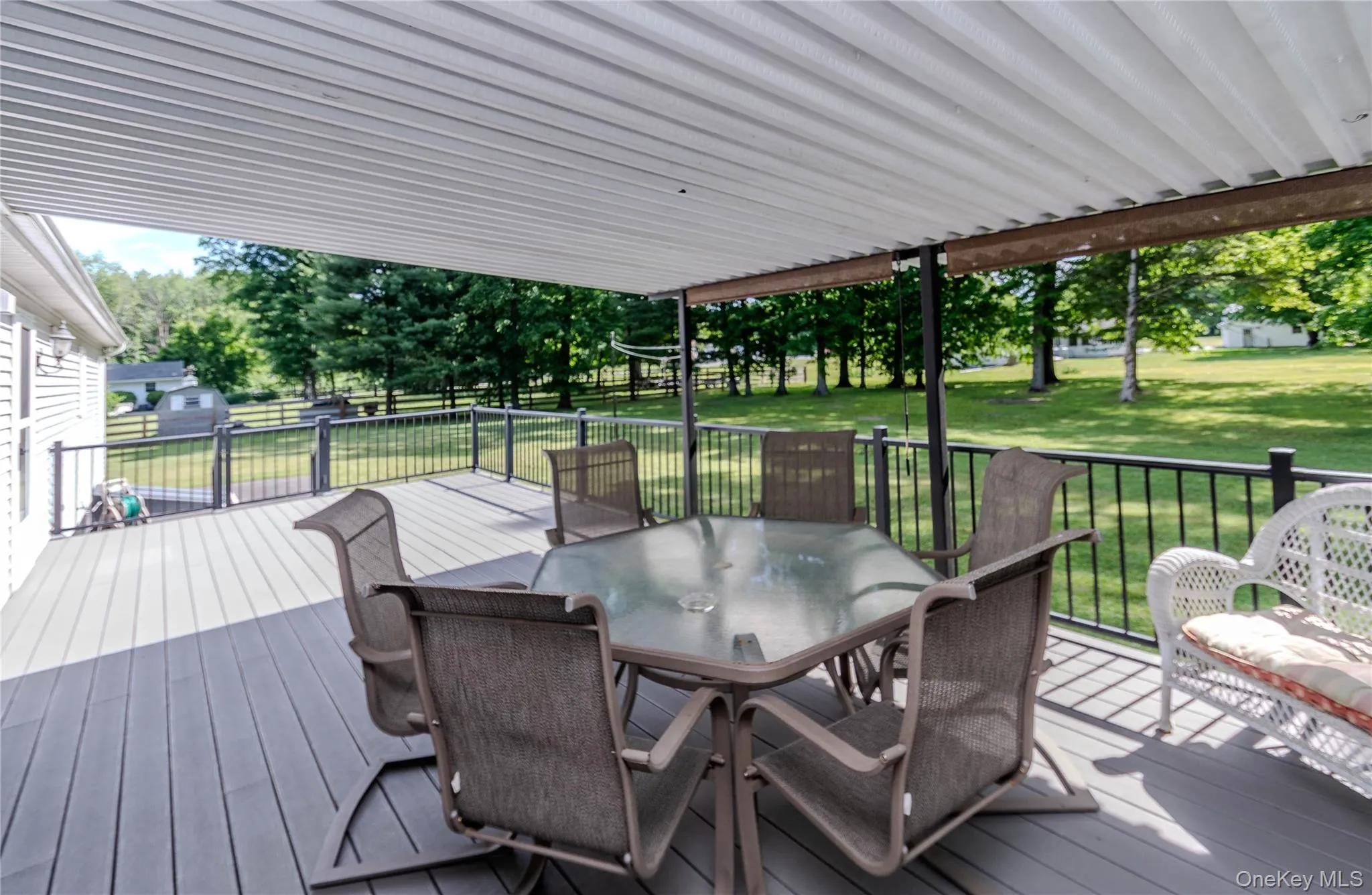 Covered outdoor deck with composite decking and black metal railings, featuring a white vinyl soffit ceiling Covered outdoor deck with composite decking and black metal railings, featuring a white vinyl soffit ceiling