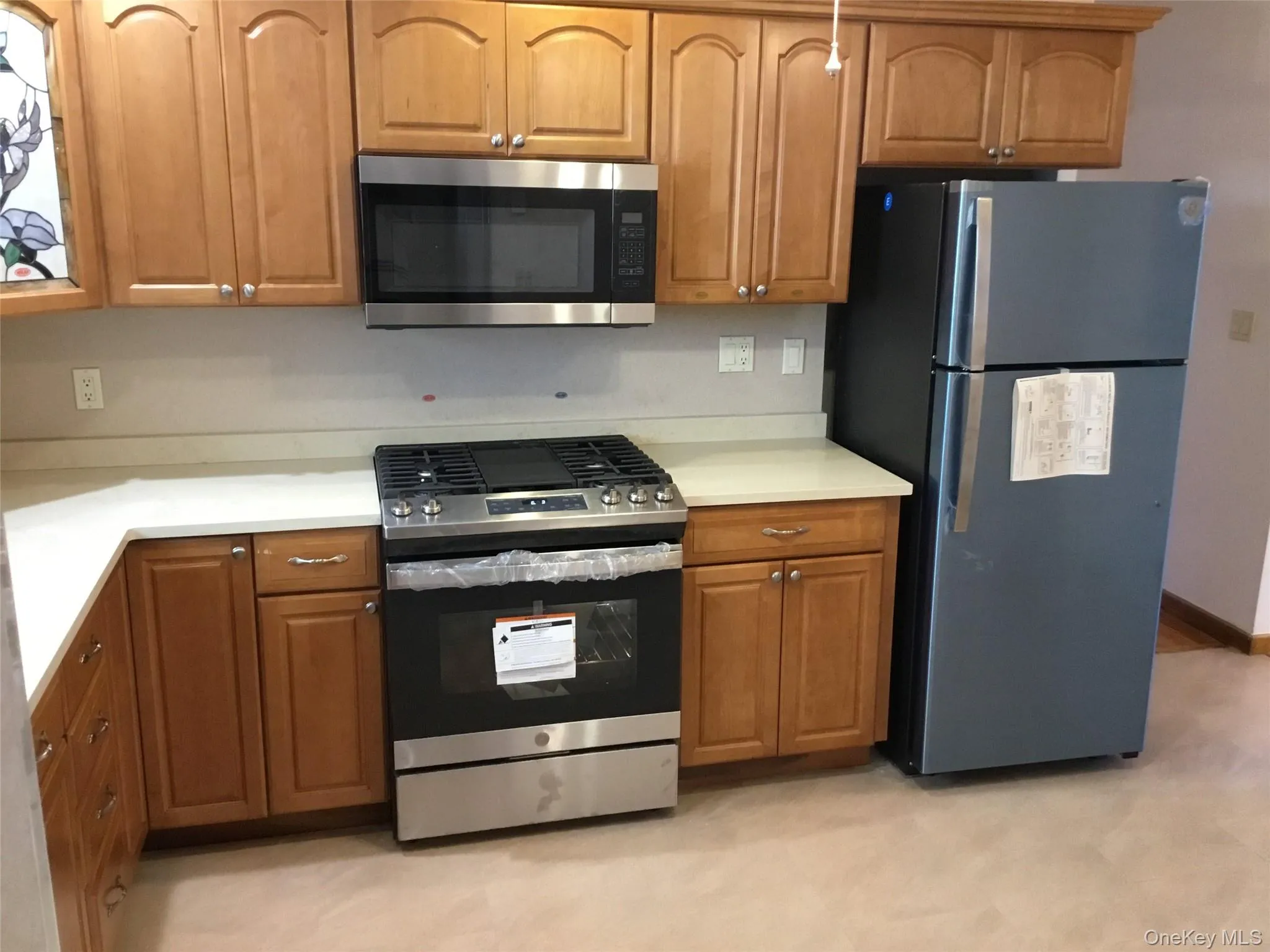 Kitchen featuring light wood cabinetry, light-toned countertops, and a stainless steel oven/range Kitchen featuring light wood cabinetry, light-toned countertops, and a stainless steel oven/range