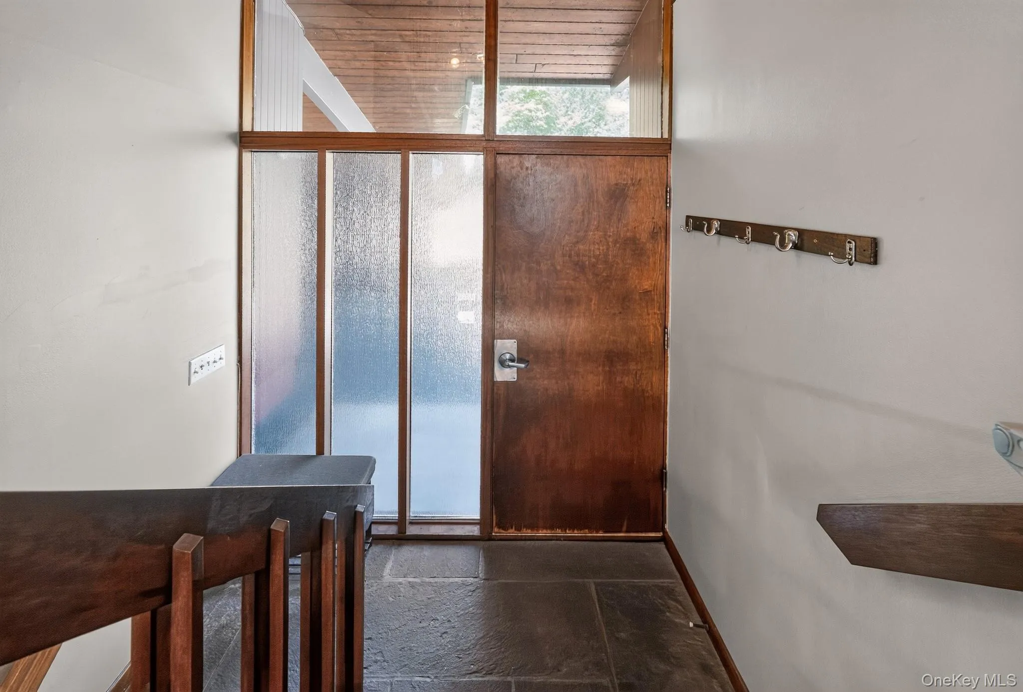 Entryway featuring a rich wood-finish door, slate tile flooring, frosted glass sidelights, clear glass transom, and a wood-finish ceiling Entryway featuring a rich wood-finish door, slate tile flooring, frosted glass sidelights, clear glass transom, and a wood-finish ceiling