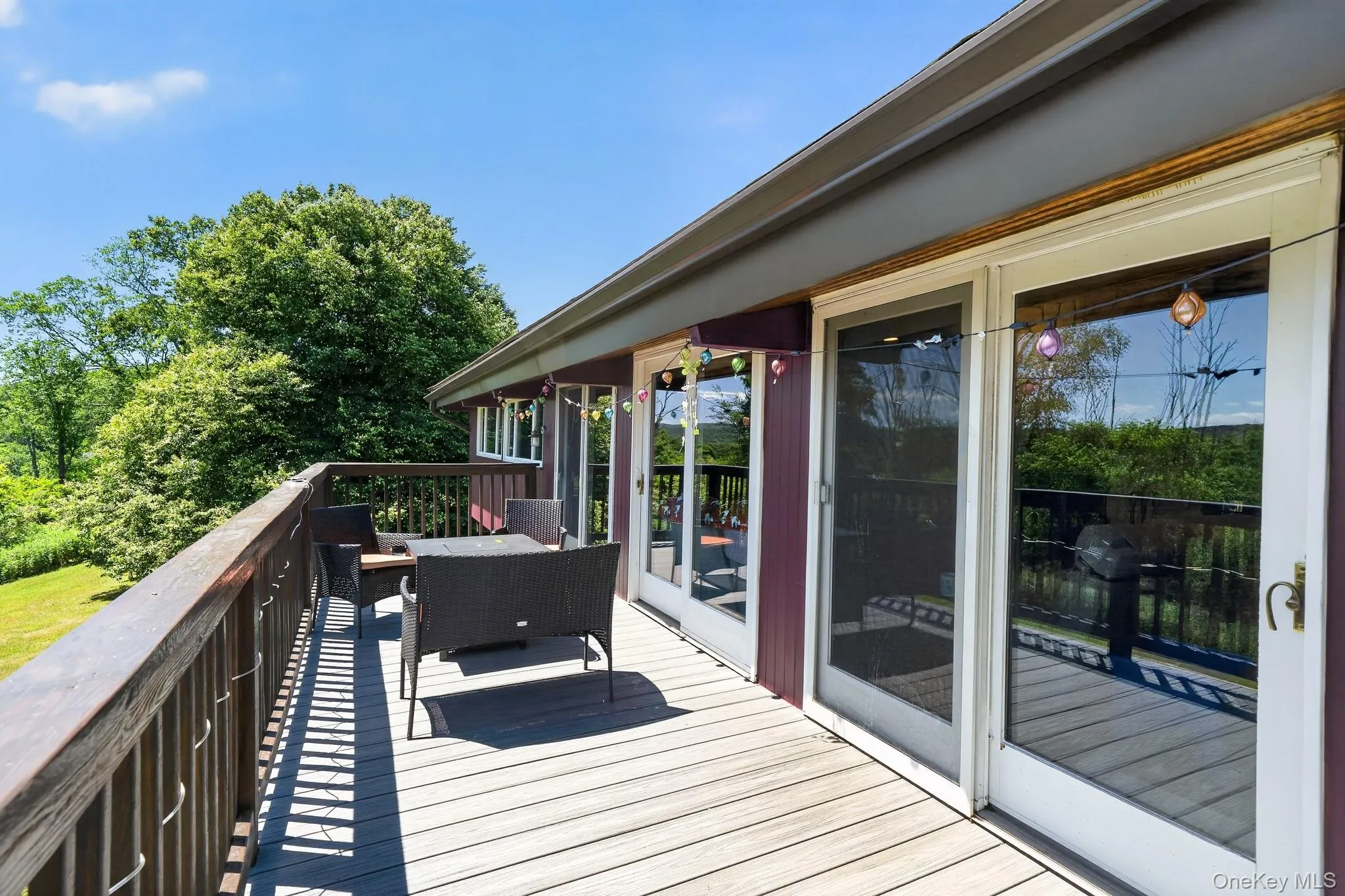 Spacious outdoor deck featuring wood-finish flooring, a full-height wood railing, and multiple glass sliding doors Spacious outdoor deck featuring wood-finish flooring, a full-height wood railing, and multiple glass sliding doors