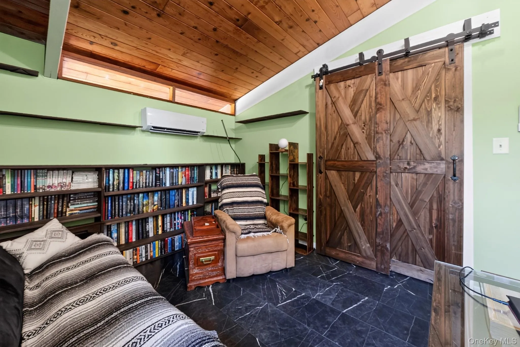 Interior space featuring a sloped wood-finish ceiling, black tile flooring, and custom wood barn doors with black metal hardware Interior space featuring a sloped wood-finish ceiling, black tile flooring, and custom wood barn doors with black metal hardware