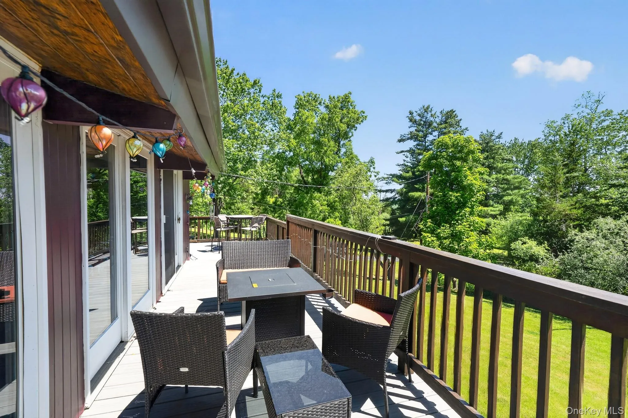 Expansive outdoor deck featuring wood-finish railing, composite decking, and multiple glass-paneled doors Expansive outdoor deck featuring wood-finish railing, composite decking, and multiple glass-paneled doors