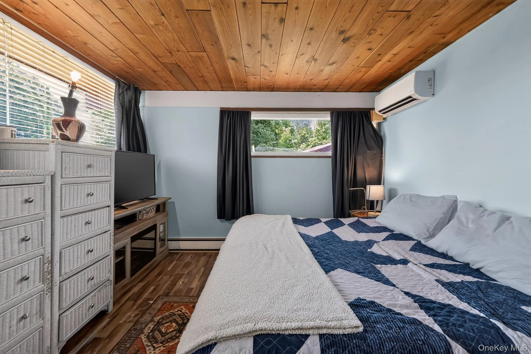 Room featuring a wood-finish ceiling, light blue walls, and wood-finish flooring Room featuring a wood-finish ceiling, light blue walls, and wood-finish flooring