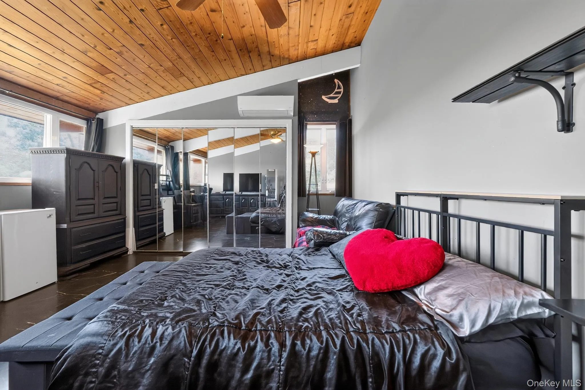 Vaulted wood-paneled ceiling with a ceiling fan, mirrored closet doors, dual windows, and built-in shelving Vaulted wood-paneled ceiling with a ceiling fan, mirrored closet doors, dual windows, and built-in shelving