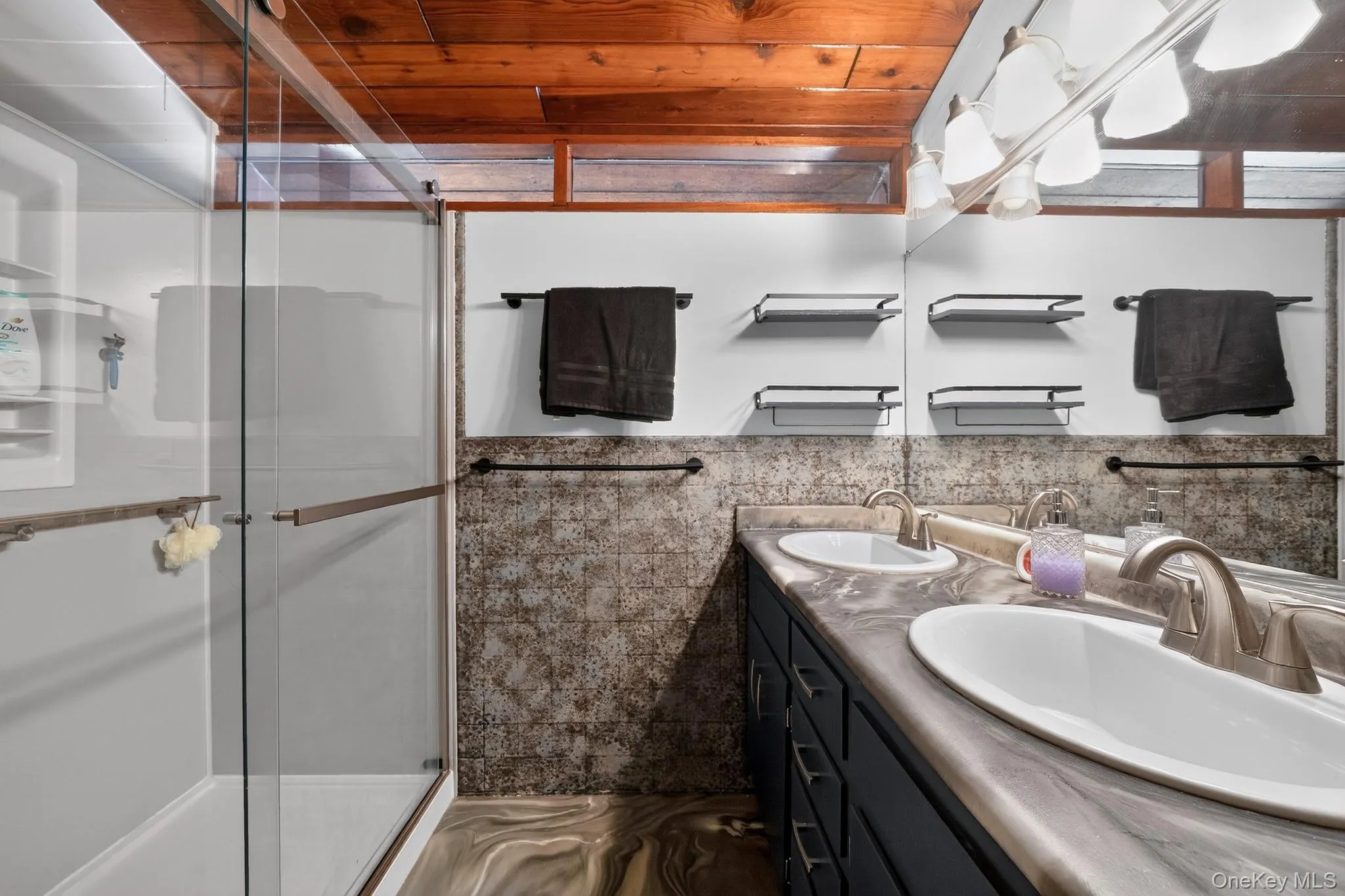 Dual vanity with integrated sinks, brushed nickel fixtures, and a large wall-mounted mirror Dual vanity with integrated sinks, brushed nickel fixtures, and a large wall-mounted mirror