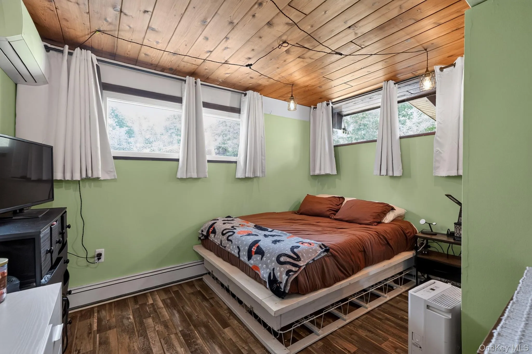 Room featuring wood-finish flooring, a wood plank ceiling, and light green painted walls Room featuring wood-finish flooring, a wood plank ceiling, and light green painted walls
