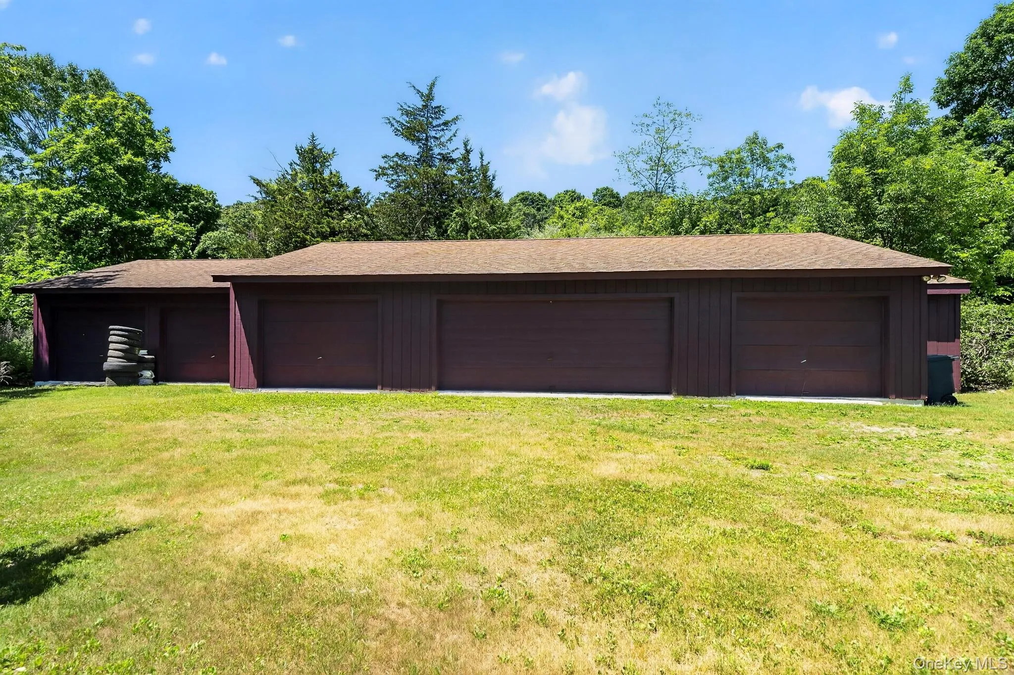 Multi-bay garage structure featuring multiple brown garage doors and a brown shingle roof Multi-bay garage structure featuring multiple brown garage doors and a brown shingle roof