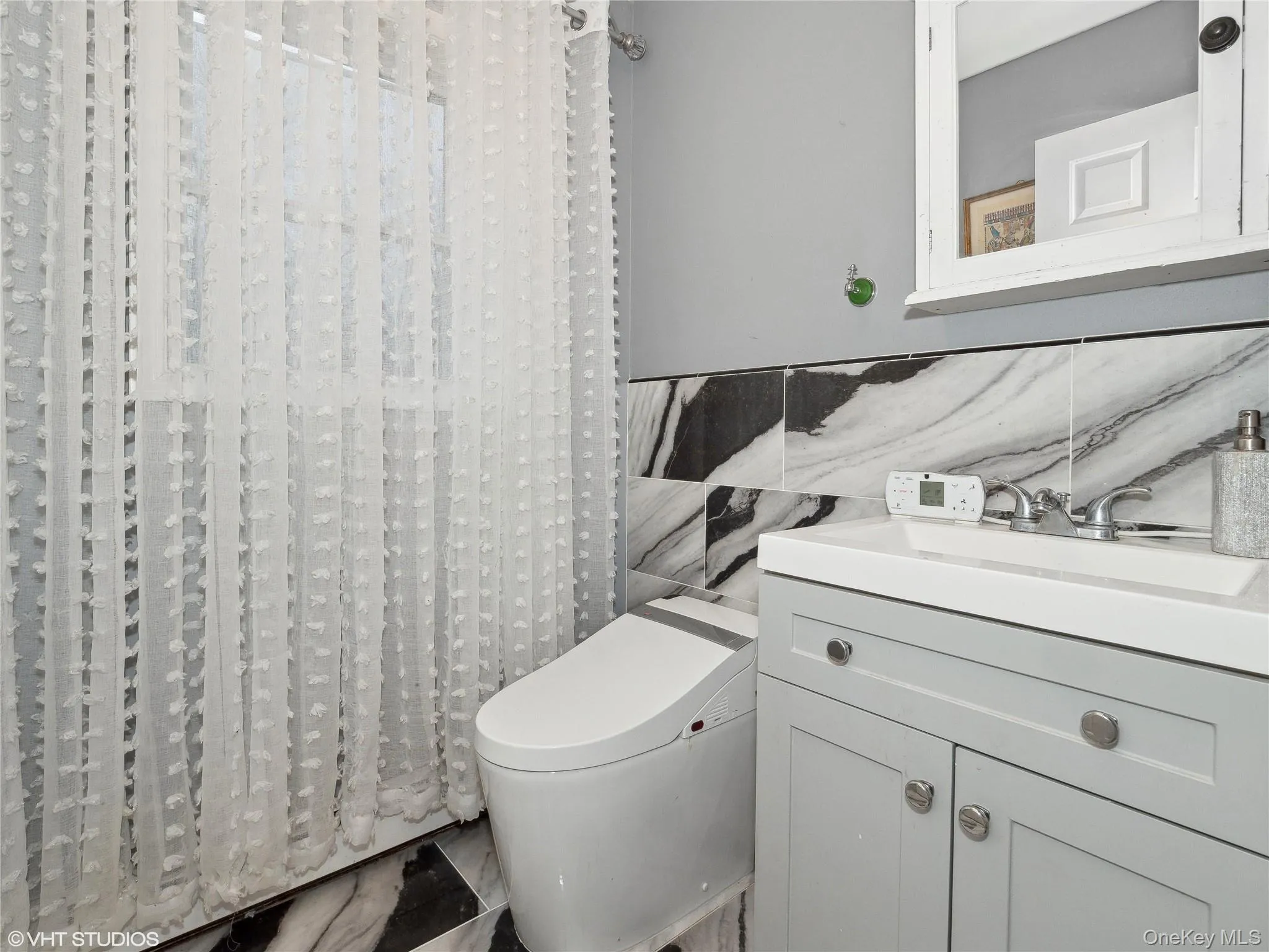 Bathroom featuring vanity, tile walls, and toilet Bathroom featuring vanity, tile walls, and toilet