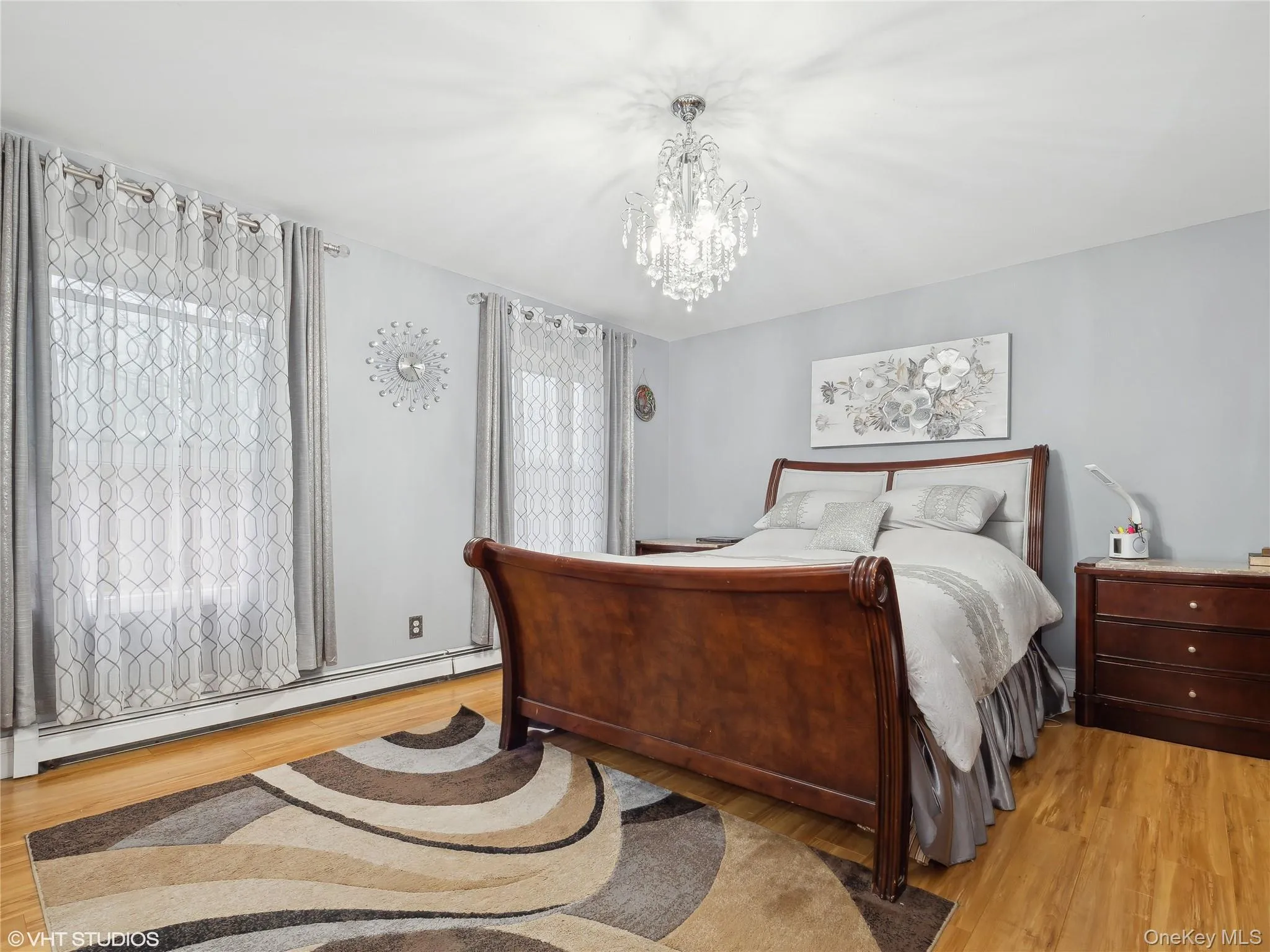 Bedroom with light hardwood / wood-style floors, multiple windows, baseboard heating, and a chandelier Bedroom with light hardwood / wood-style floors, multiple windows, baseboard heating, and a chandelier