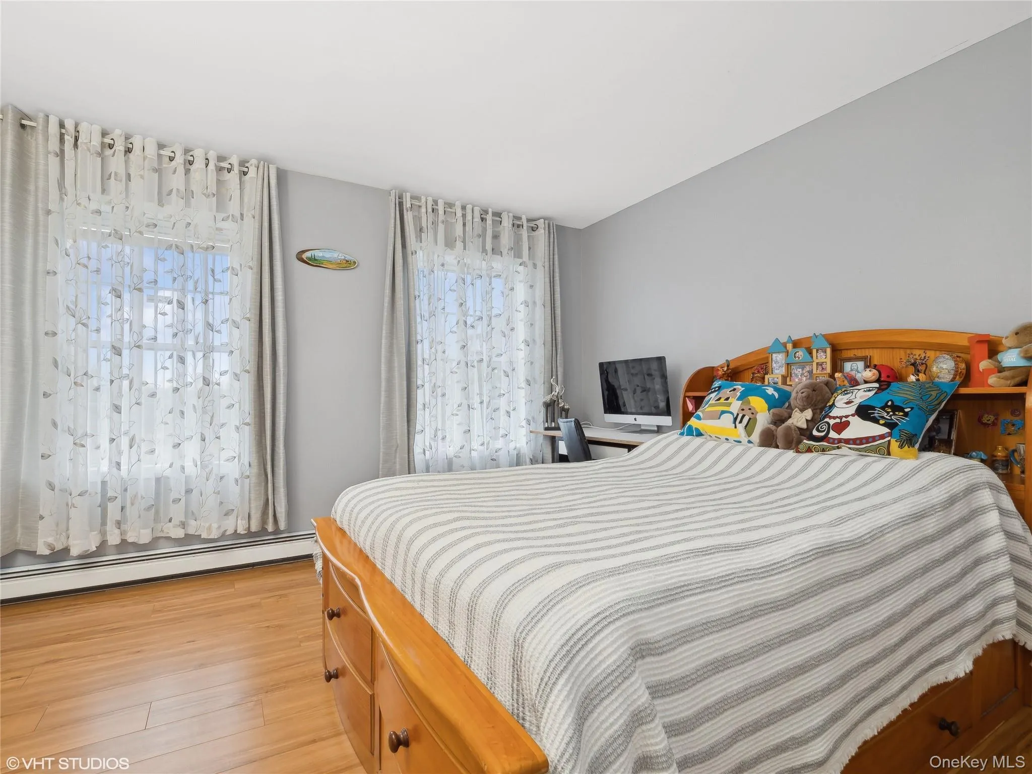 Bedroom featuring a baseboard radiator, light hardwood / wood-style flooring, and multiple windows Bedroom featuring a baseboard radiator, light hardwood / wood-style flooring, and multiple windows