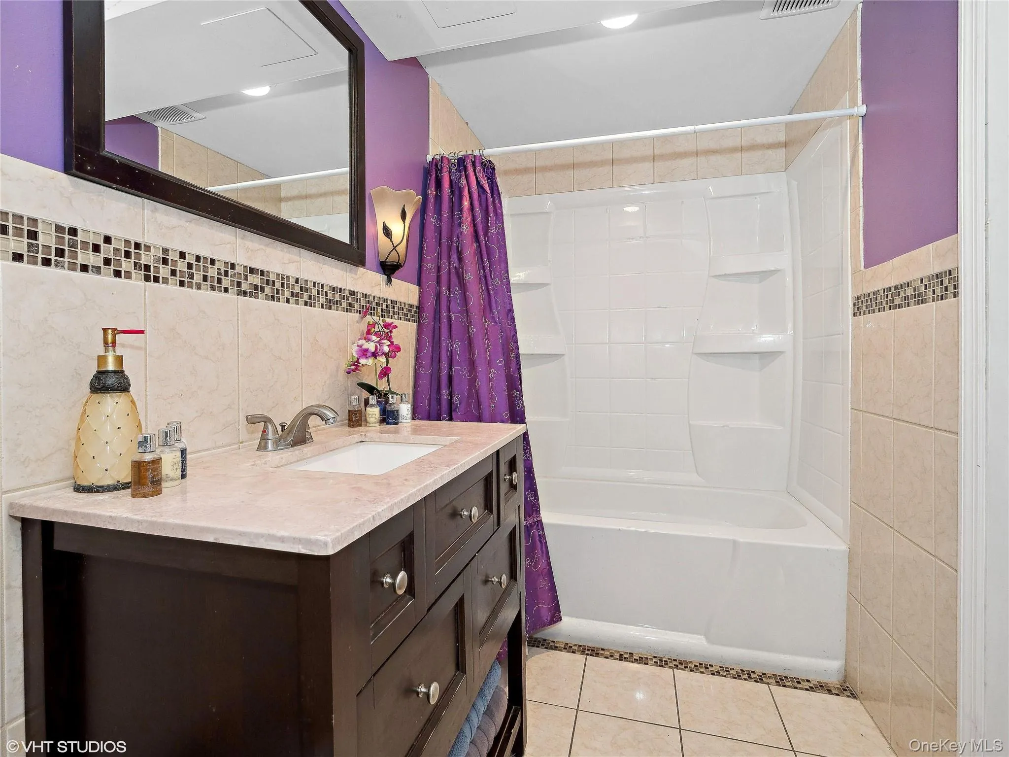 Bathroom featuring tile patterned floors, vanity, tile walls, and shower / tub combo with curtain Bathroom featuring tile patterned floors, vanity, tile walls, and shower / tub combo with curtain