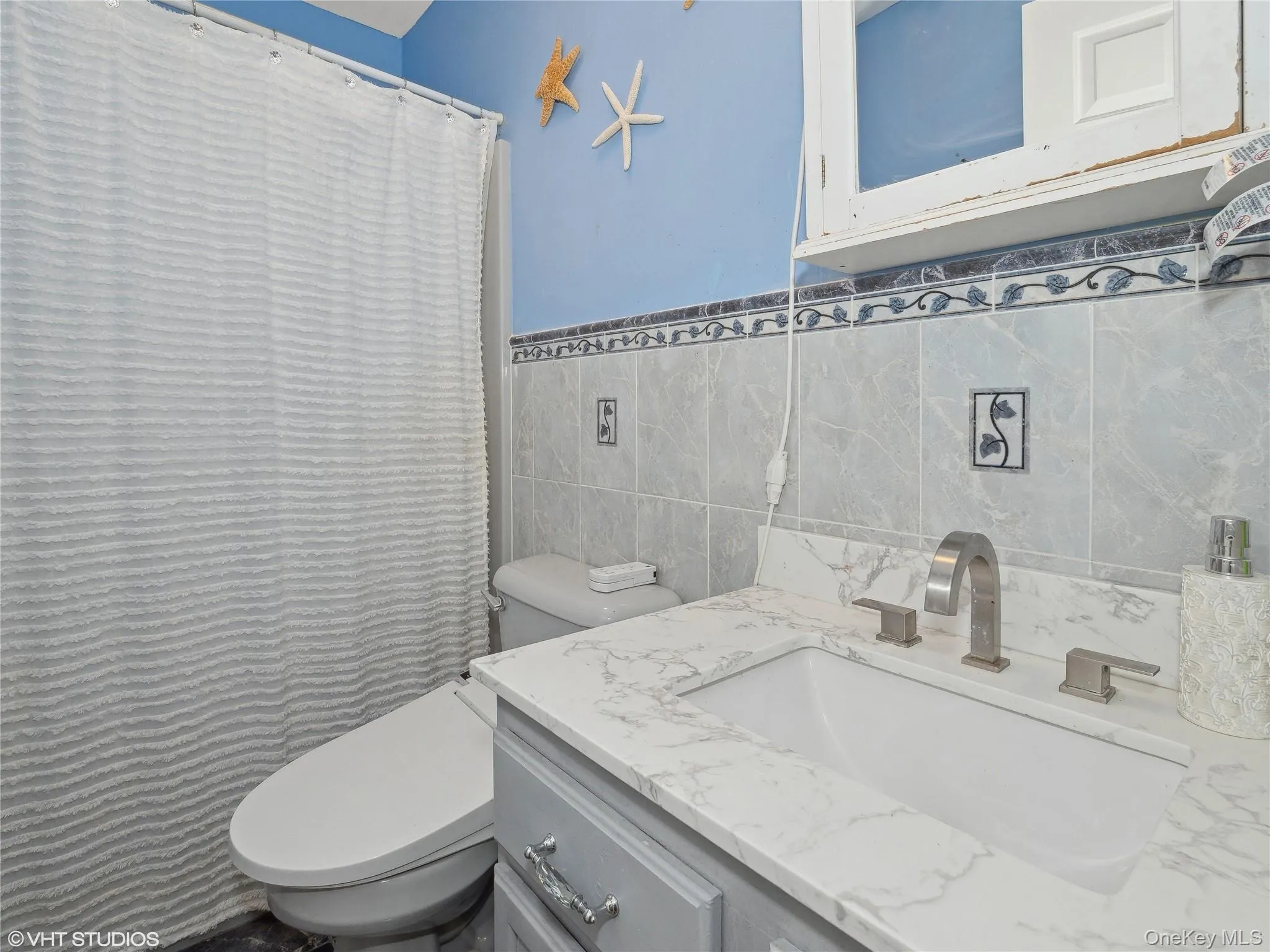 Bathroom featuring vanity, toilet, and tile walls Bathroom featuring vanity, toilet, and tile walls