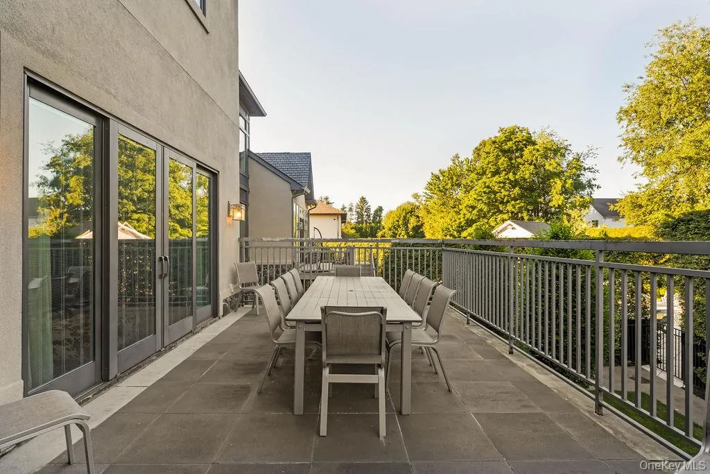Expansive outdoor terrace featuring large format stone tile flooring, a dark metal railing, and multiple sets of glass panel doors Expansive outdoor terrace featuring large format stone tile flooring, a dark metal railing, and multiple sets of glass panel doors