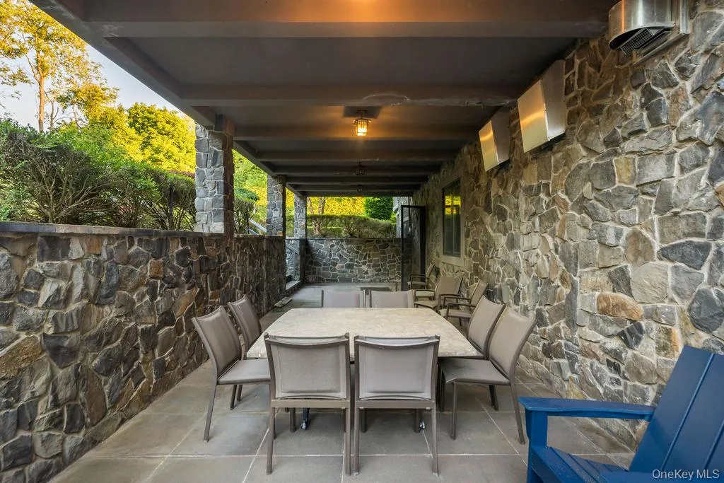 Covered outdoor patio featuring stone walls, an overhead ceiling fan, recessed lighting, and a stone slab floor Covered outdoor patio featuring stone walls, an overhead ceiling fan, recessed lighting, and a stone slab floor