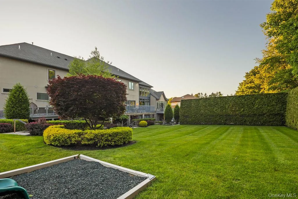 Expansive backyard featuring a manicured lawn, established privacy hedges, and mature landscaping Expansive backyard featuring a manicured lawn, established privacy hedges, and mature landscaping