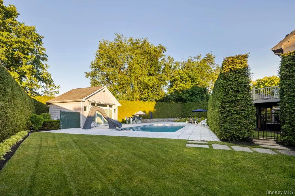 Expansive green lawn with a swimming pool, surrounding patio, and a pool house Expansive green lawn with a swimming pool, surrounding patio, and a pool house