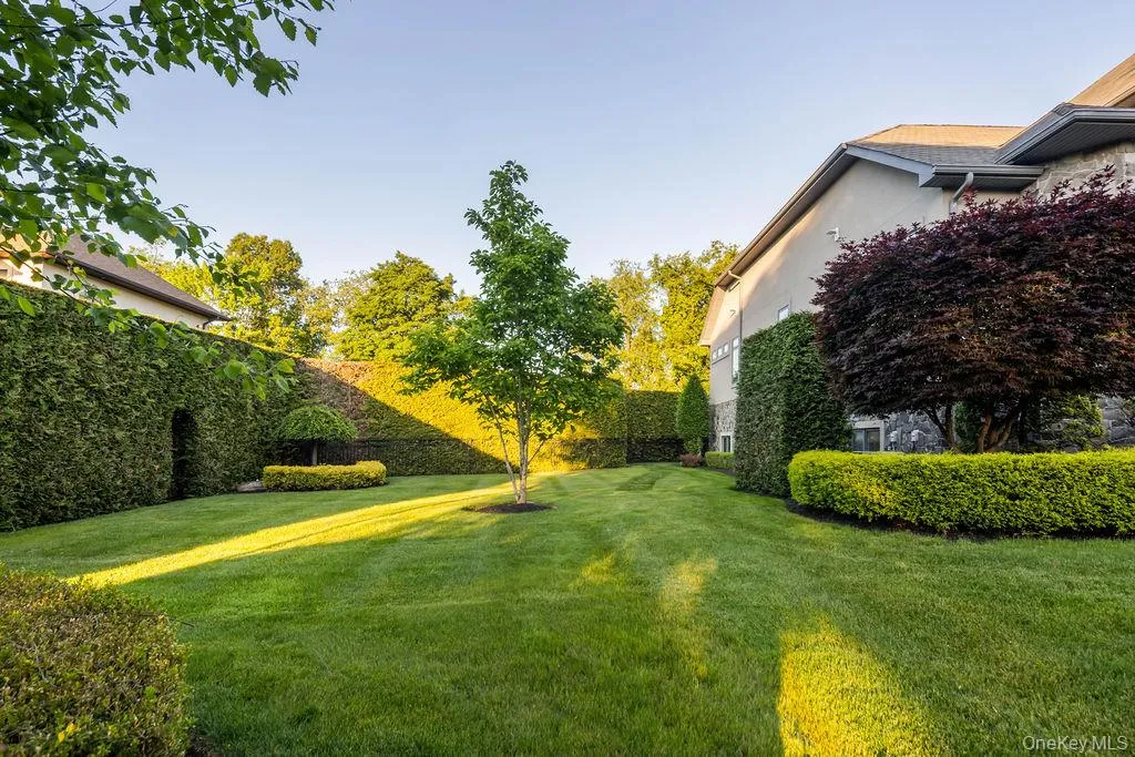 Expansive backyard featuring a lush lawn, mature trees, and meticulously maintained hedges Expansive backyard featuring a lush lawn, mature trees, and meticulously maintained hedges