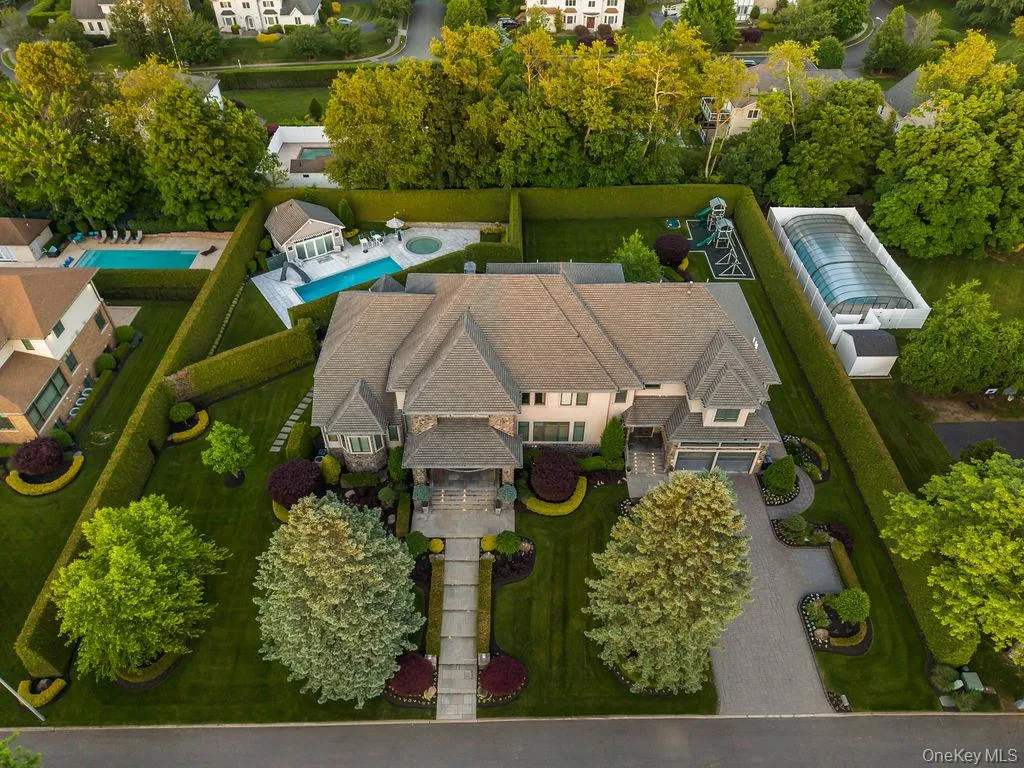Grand residence featuring a stone and stucco exterior, a multi-car garage, and a lush, manicured landscape Grand residence featuring a stone and stucco exterior, a multi-car garage, and a lush, manicured landscape