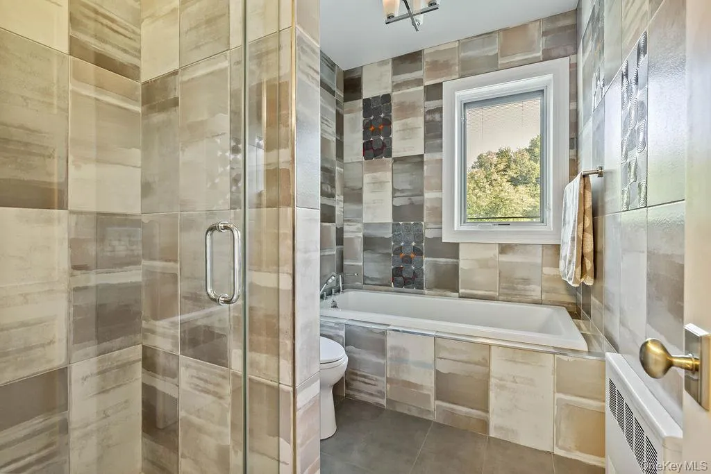 Contemporary bathroom featuring a glass-enclosed shower, a deep soaking tub, and a window for natural light Contemporary bathroom featuring a glass-enclosed shower, a deep soaking tub, and a window for natural light