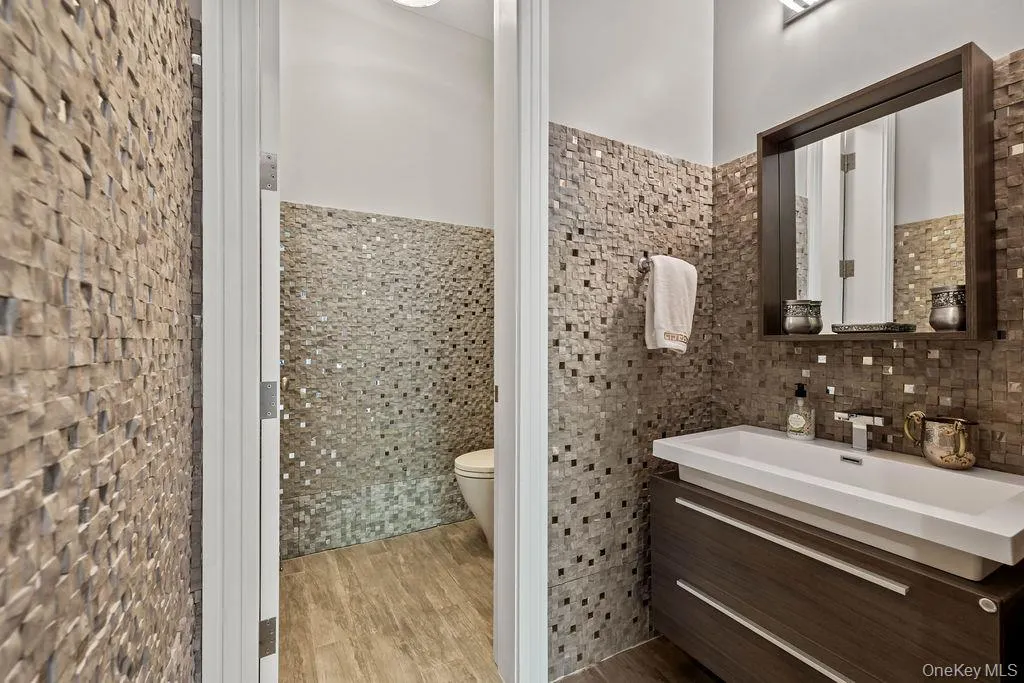 Modern bathroom featuring a dark wood-finish floating vanity with an integrated white sink, a framed mirror, and a wall-mounted faucet Modern bathroom featuring a dark wood-finish floating vanity with an integrated white sink, a framed mirror, and a wall-mounted faucet