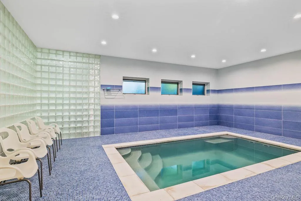Indoor plunge pool with integrated steps, surrounded by blue mosaic tile flooring and a contrasting blue tile wainscoting Indoor plunge pool with integrated steps, surrounded by blue mosaic tile flooring and a contrasting blue tile wainscoting