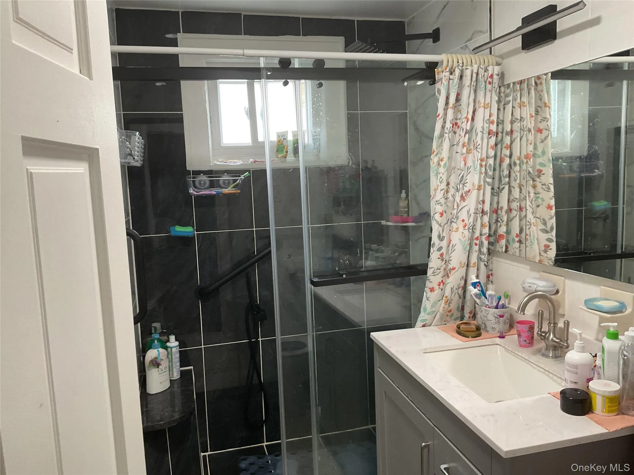 Shower enclosure featuring dark tile walls and a clear glass door Shower enclosure featuring dark tile walls and a clear glass door