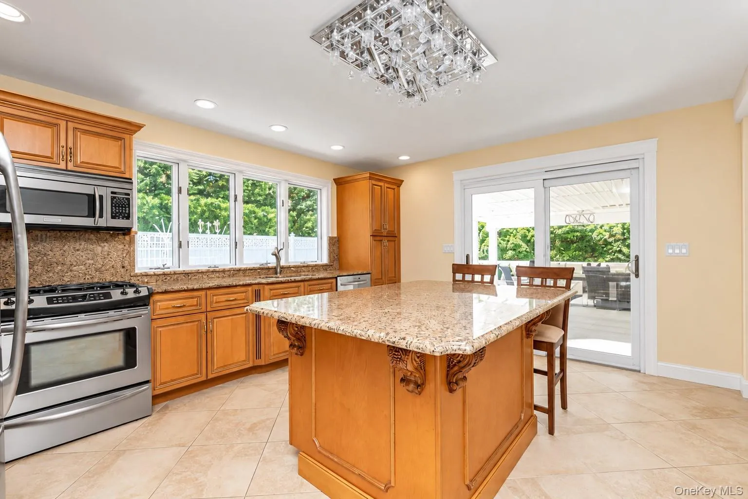 prominent kitchen island with a stone countertop and built-in cabinetry, with sliders out to enclosed patio prominent kitchen island with a stone countertop and built-in cabinetry, with sliders out to enclosed patio