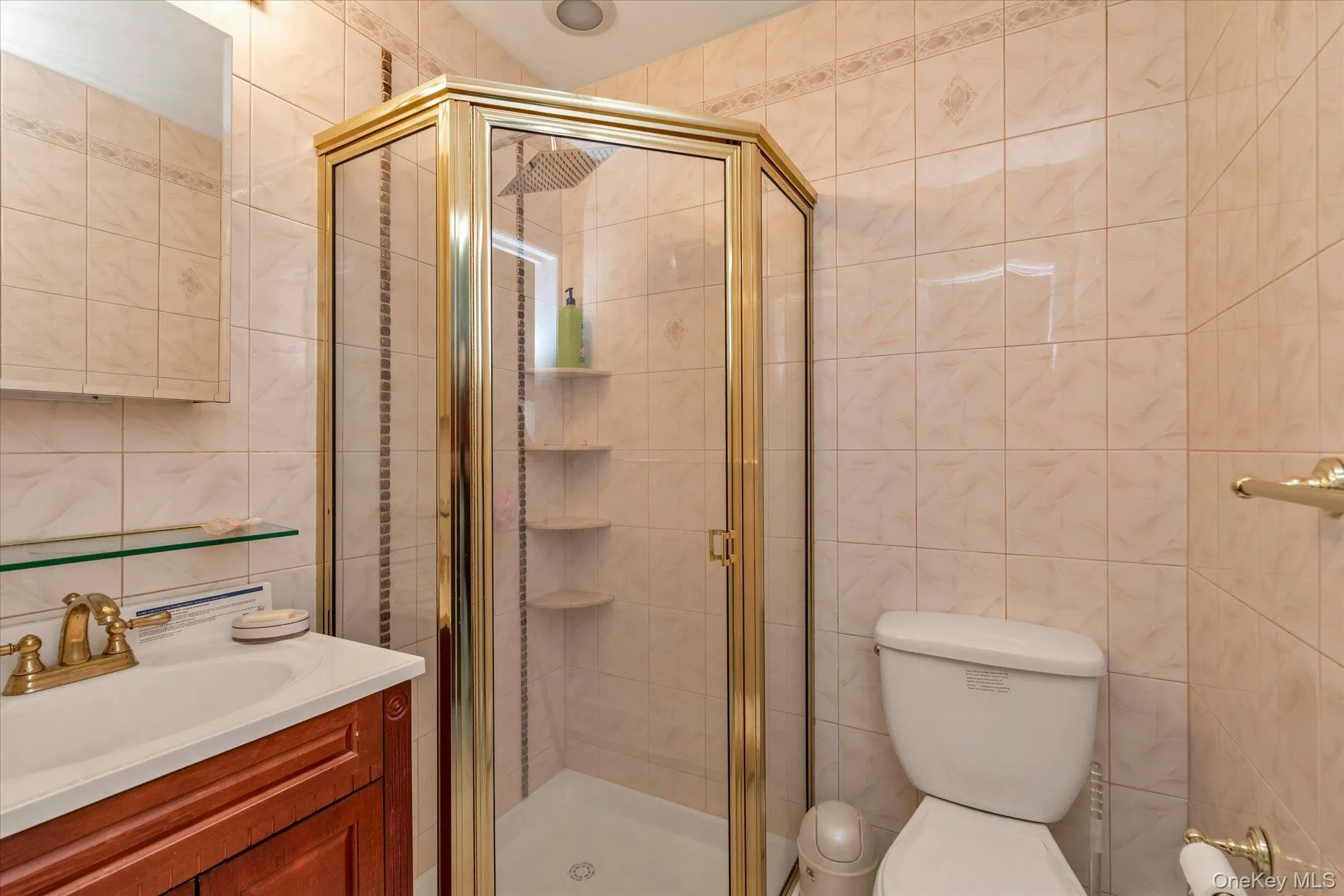 Lower Level Bathroom featuring a corner shower with a gold-toned frame, rain shower head, and built-in shelving Lower Level Bathroom featuring a corner shower with a gold-toned frame, rain shower head, and built-in shelving