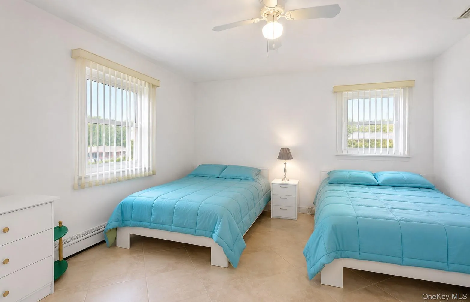 Room featuring two windows with vertical blinds, a ceiling fan, and light-toned tile flooring Room featuring two windows with vertical blinds, a ceiling fan, and light-toned tile flooring