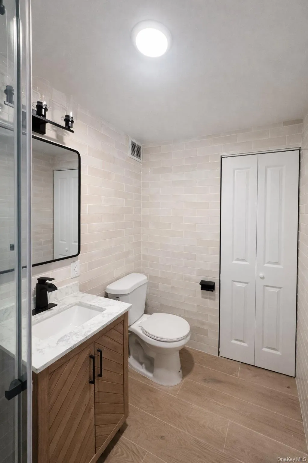 Bathroom featuring a wood-finish vanity with a quartz countertop, rectangular undermount sink, and matte black faucet Bathroom featuring a wood-finish vanity with a quartz countertop, rectangular undermount sink, and matte black faucet