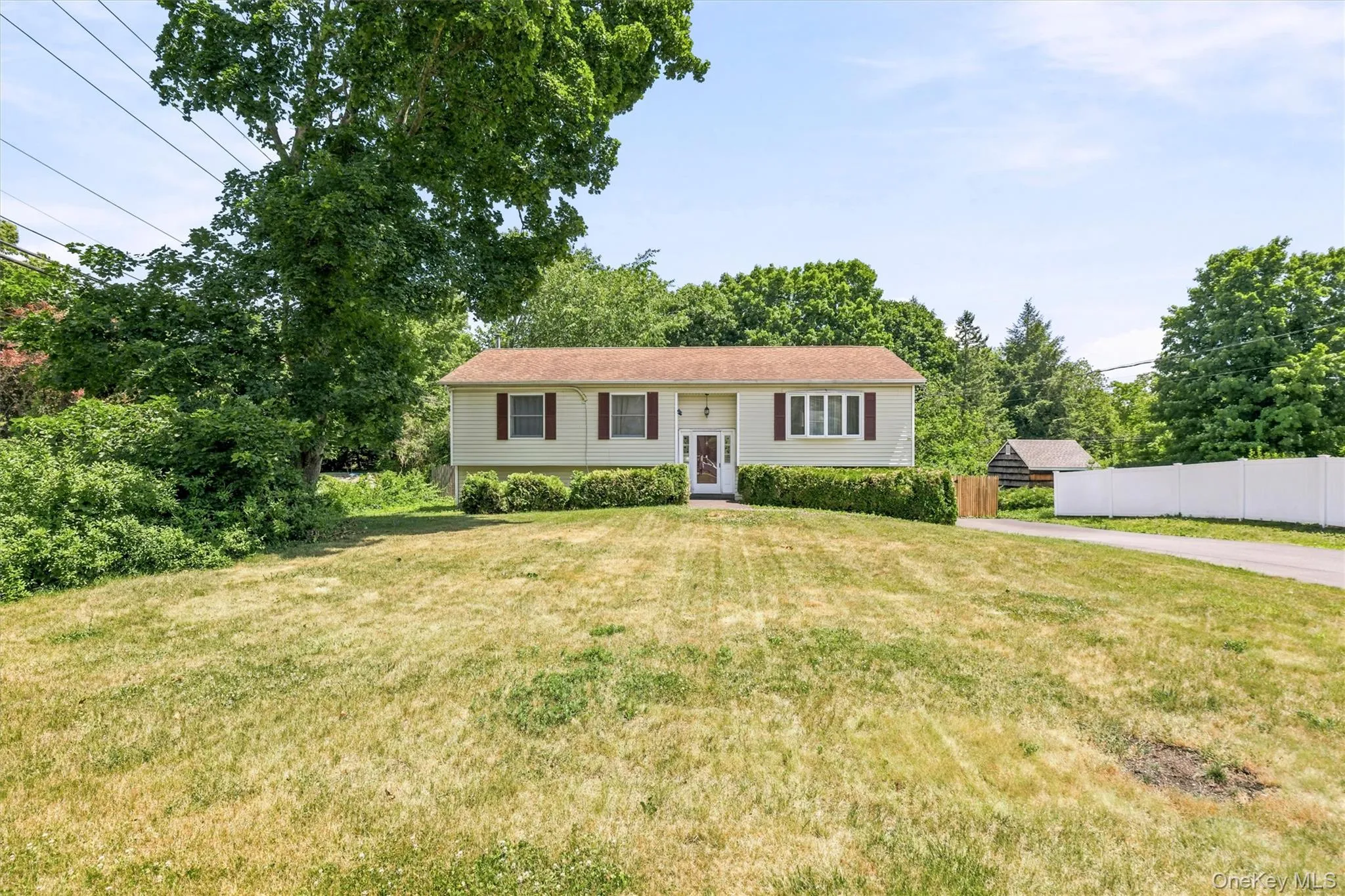 Raised Ranch-style residence featuring a light-colored facade with contrasting red window shutters Raised Ranch-style residence featuring a light-colored facade with contrasting red window shutters