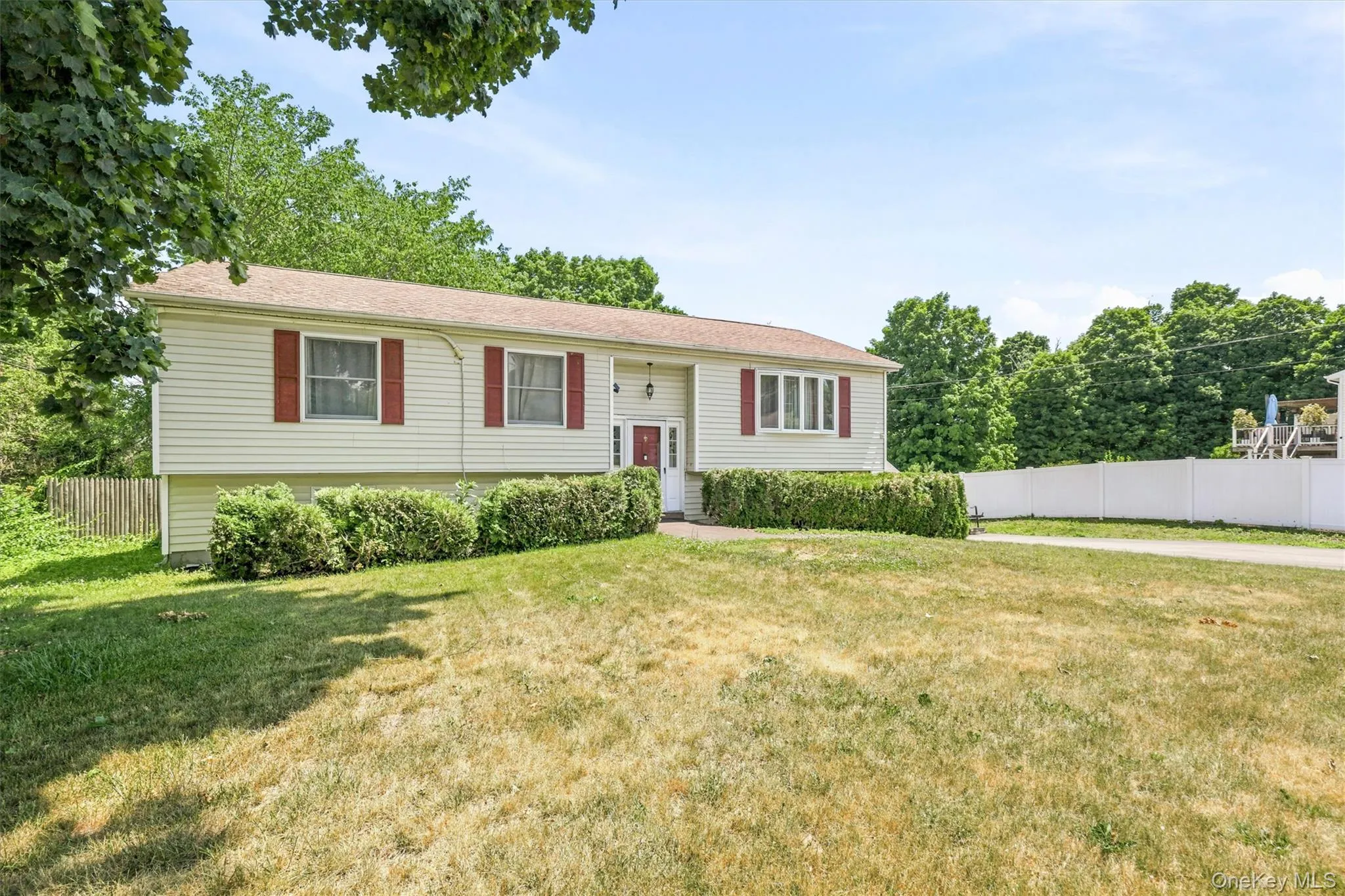 Exterior featuring light-colored horizontal siding, red window shutters, and a white entry door Exterior featuring light-colored horizontal siding, red window shutters, and a white entry door