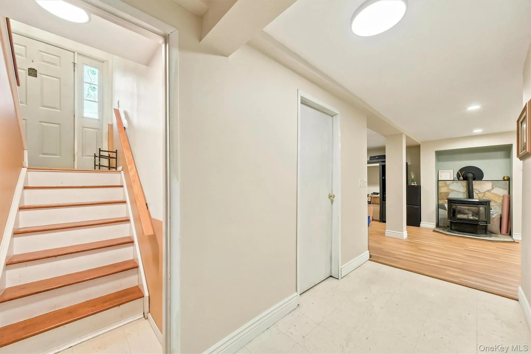 Light-filled lower level featuring a wood-burning stove with a stone surround, wood-finish flooring, and recessed lighting Light-filled lower level featuring a wood-burning stove with a stone surround, wood-finish flooring, and recessed lighting