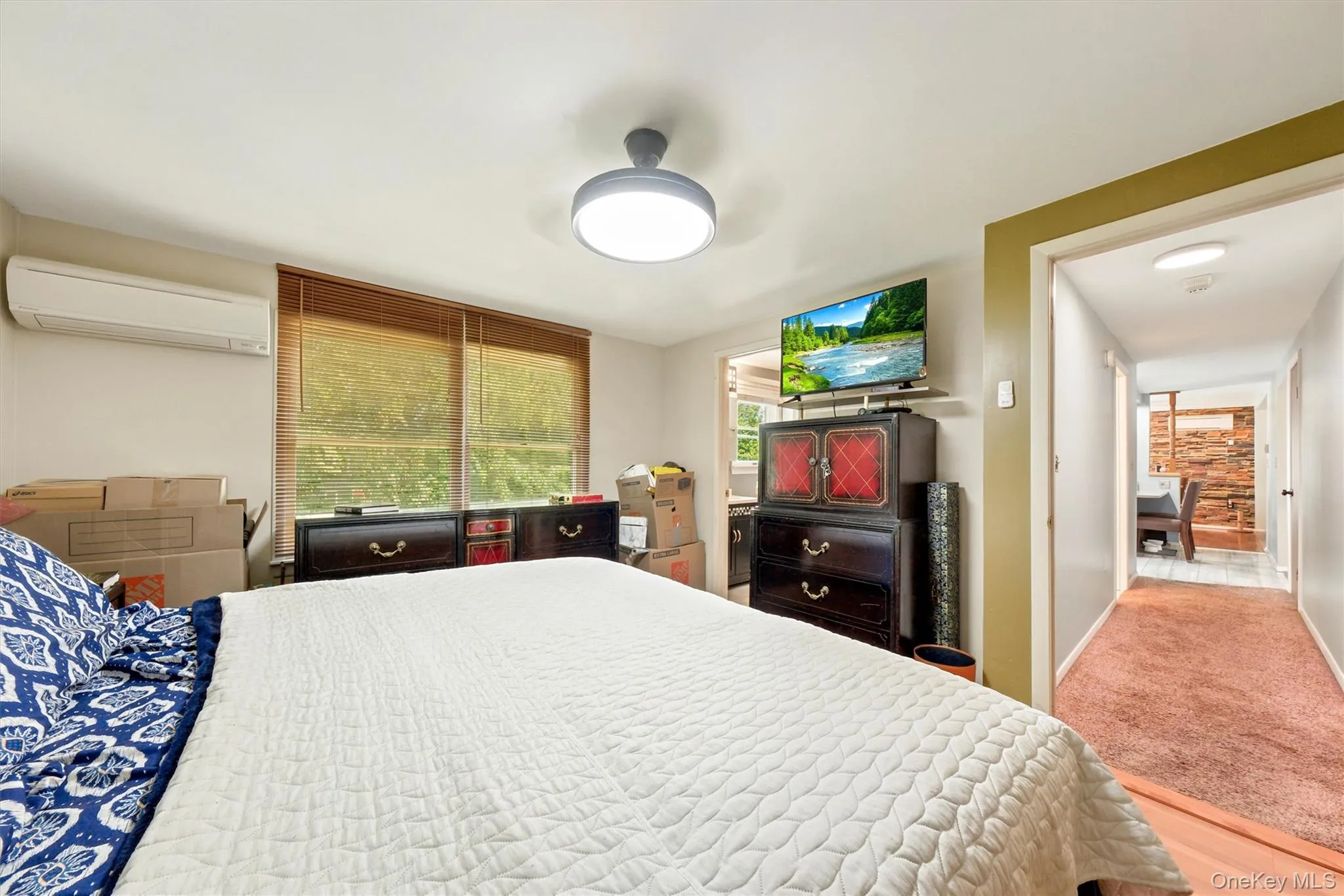 Room featuring a ceiling-mounted light fixture, window with blinds, and a wall-mounted air conditioning unit Room featuring a ceiling-mounted light fixture, window with blinds, and a wall-mounted air conditioning unit
