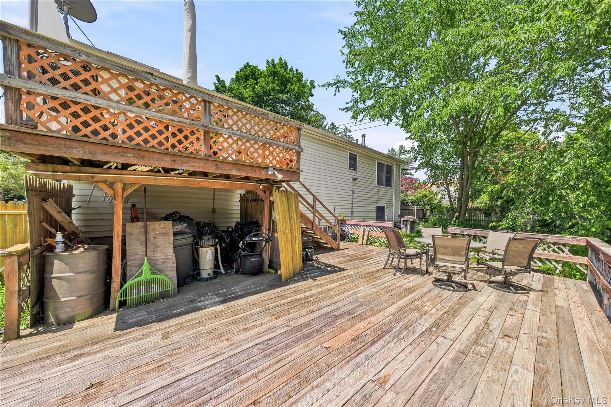 Multi-level wood deck featuring a lattice railing, natural wood-finish flooring, and a stairway leading to the upper level Multi-level wood deck featuring a lattice railing, natural wood-finish flooring, and a stairway leading to the upper level