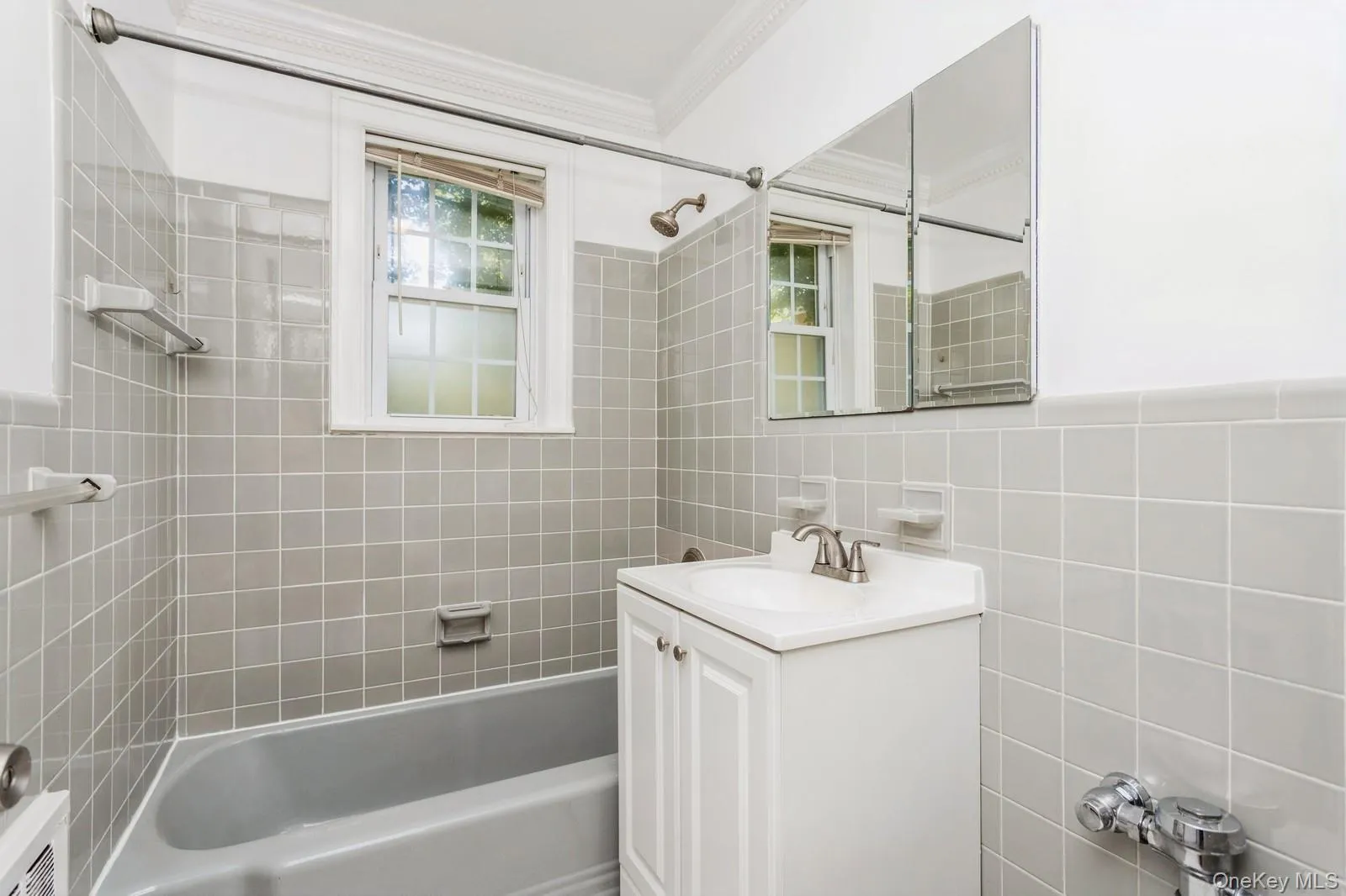 Full bath featuring crown molding, vanity, bathing tub / shower combination, and tile walls Full bath featuring crown molding, vanity, bathing tub / shower combination, and tile walls
