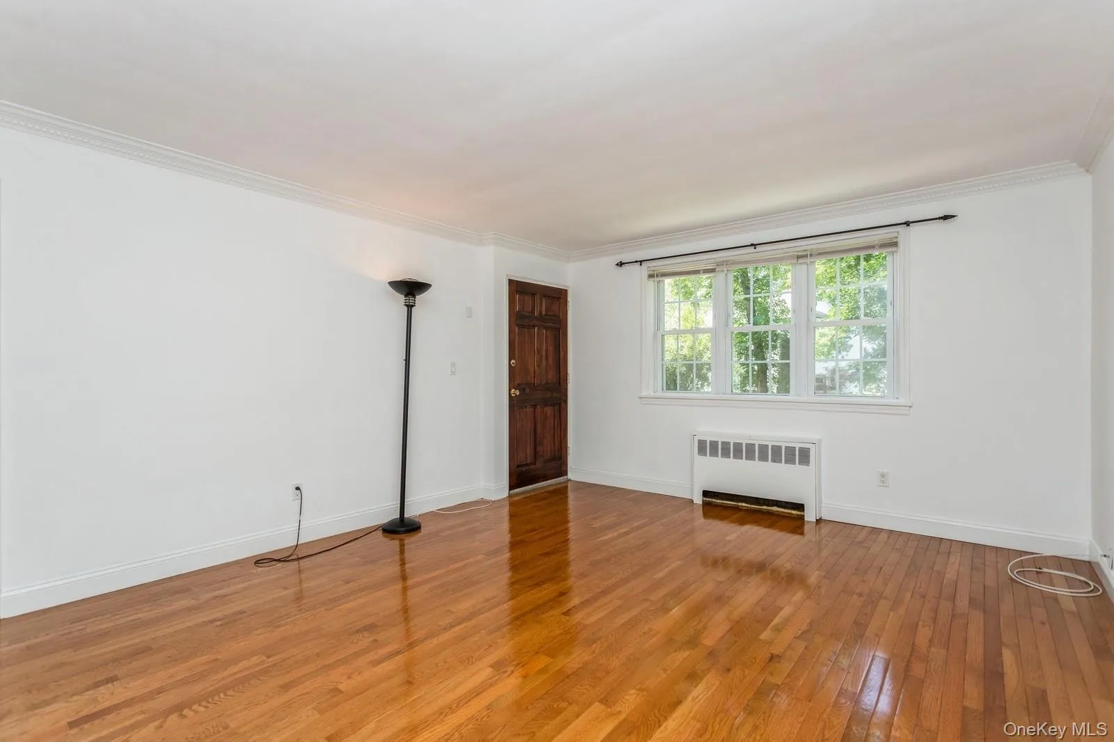 Unfurnished room featuring radiator heating unit, hardwood / wood-style floors, and crown molding Unfurnished room featuring radiator heating unit, hardwood / wood-style floors, and crown molding