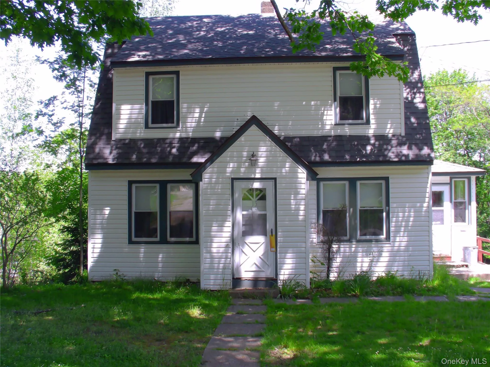 Two-story home with white horizontal siding and dark trim, featuring a gambrel roof and a covered entryway Two-story home with white horizontal siding and dark trim, featuring a gambrel roof and a covered entryway