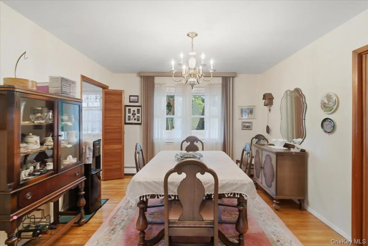 Dining area featuring wood-finish flooring, a brass chandelier, and white wall finishes Dining area featuring wood-finish flooring, a brass chandelier, and white wall finishes