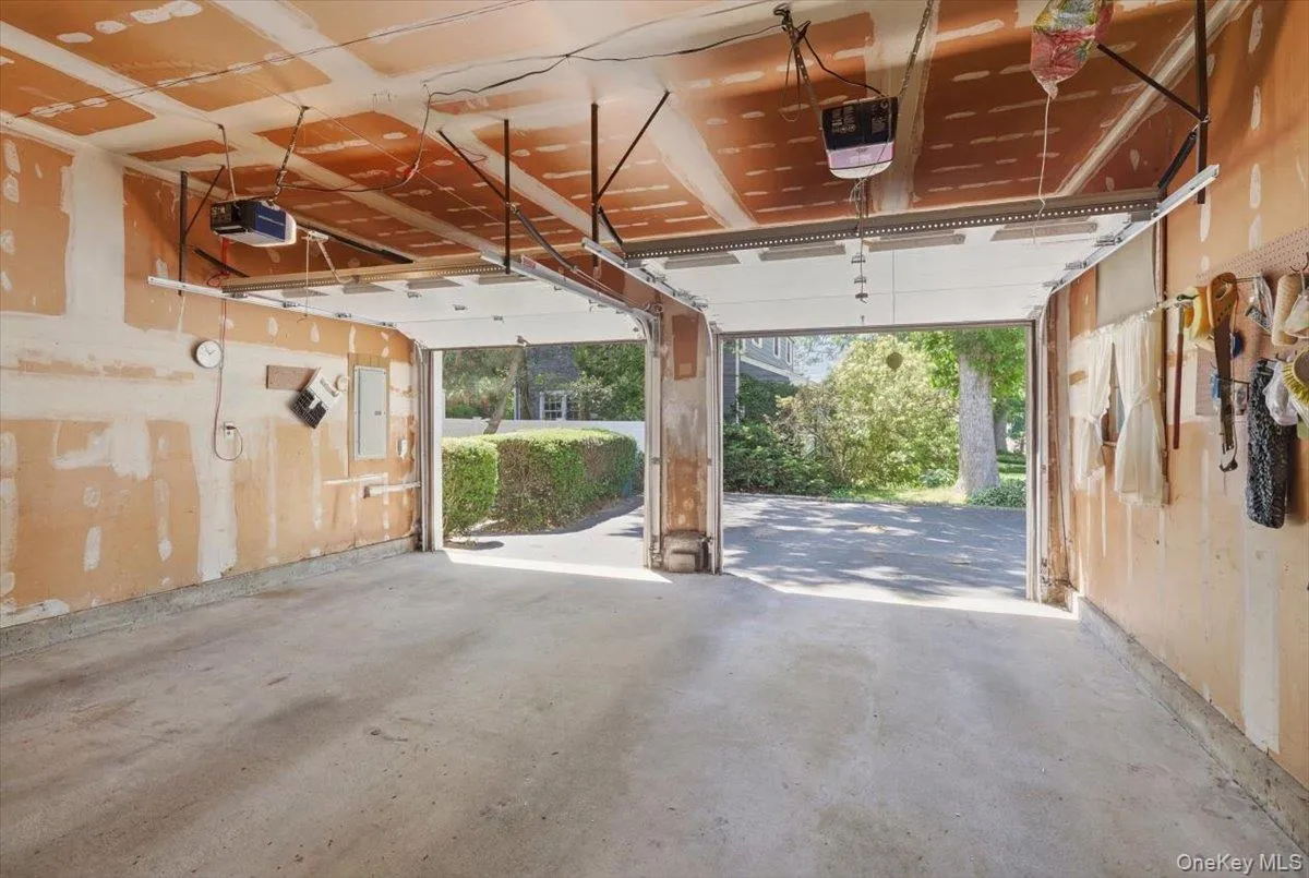 Two-car garage featuring a concrete floor, two overhead garage door openers, and exposed drywall Two-car garage featuring a concrete floor, two overhead garage door openers, and exposed drywall