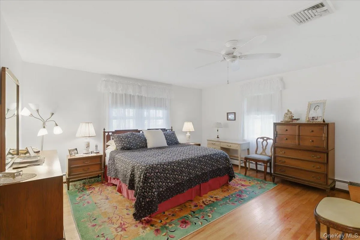 Spacious room featuring hardwood flooring, white walls, and a ceiling fan Spacious room featuring hardwood flooring, white walls, and a ceiling fan
