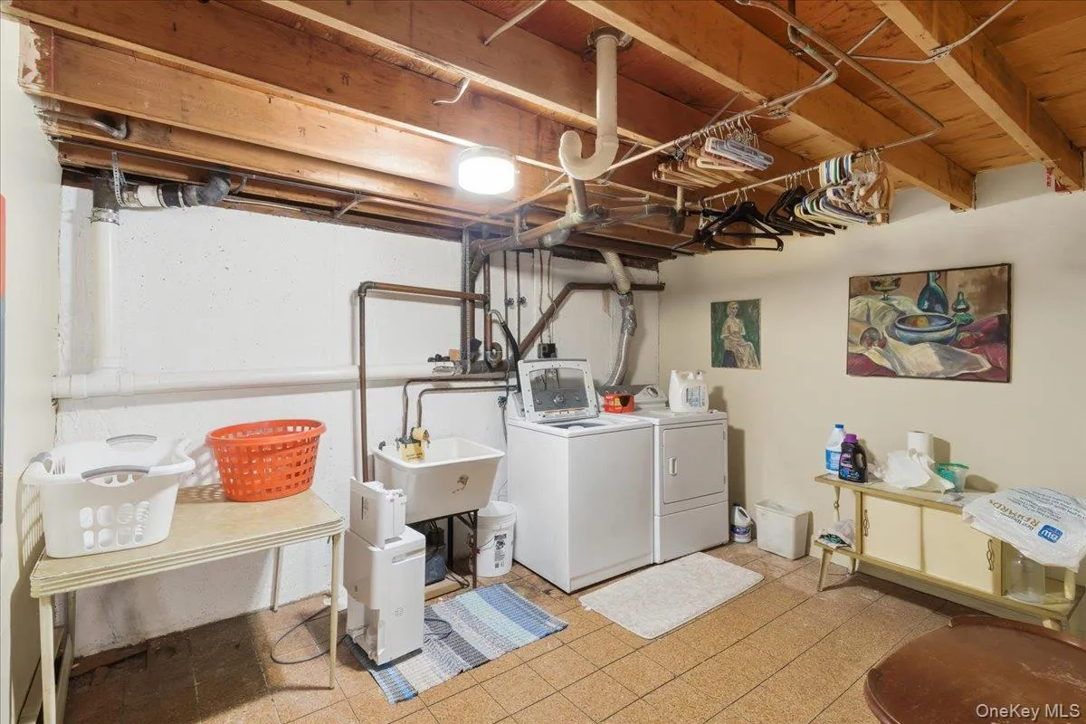 Laundry area featuring exposed wood joists, utility sink, and tile flooring Laundry area featuring exposed wood joists, utility sink, and tile flooring