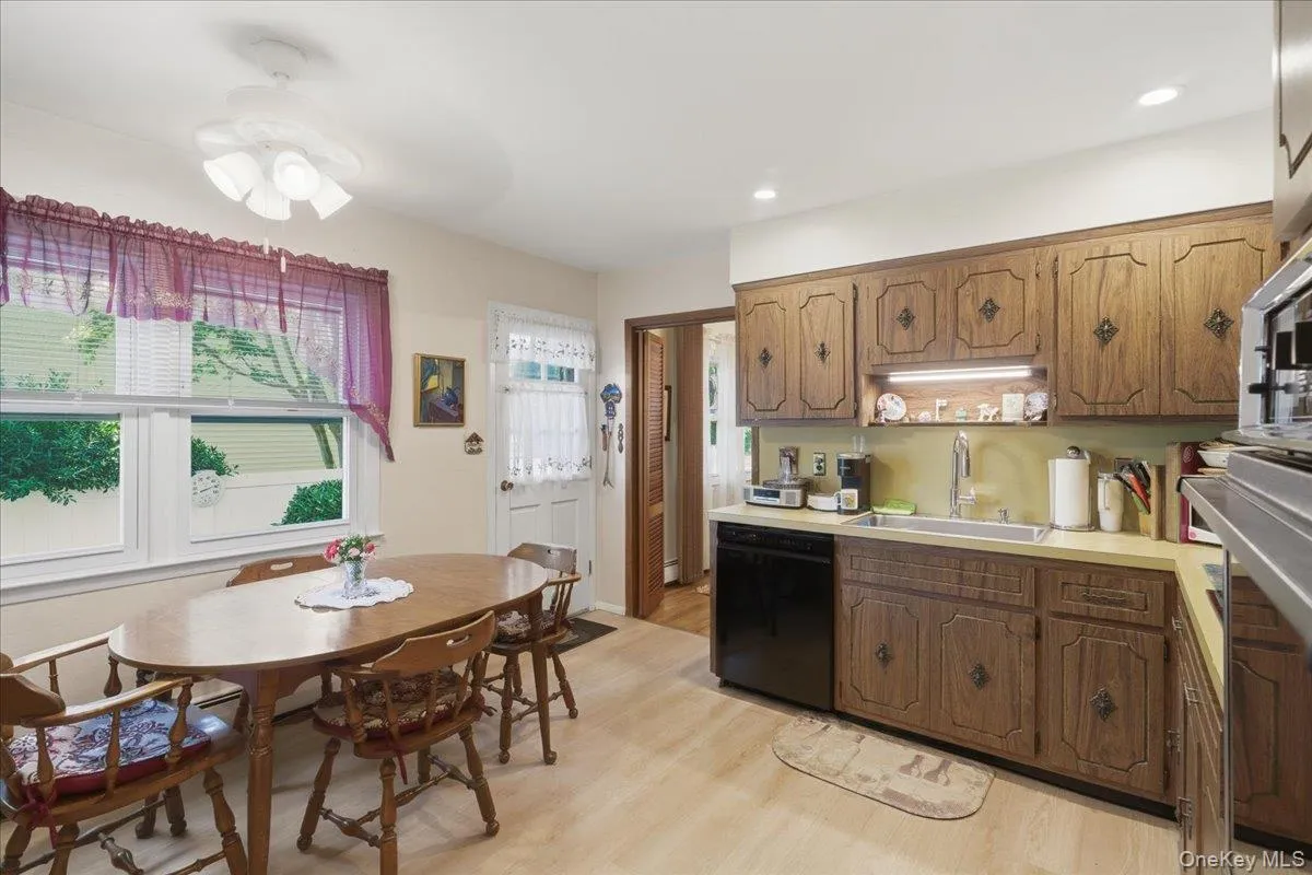 Kitchen featuring wood-finish cabinetry, light-toned countertops, a black dishwasher, recessed lighting, and light wood-finish flooring Kitchen featuring wood-finish cabinetry, light-toned countertops, a black dishwasher, recessed lighting, and light wood-finish flooring
