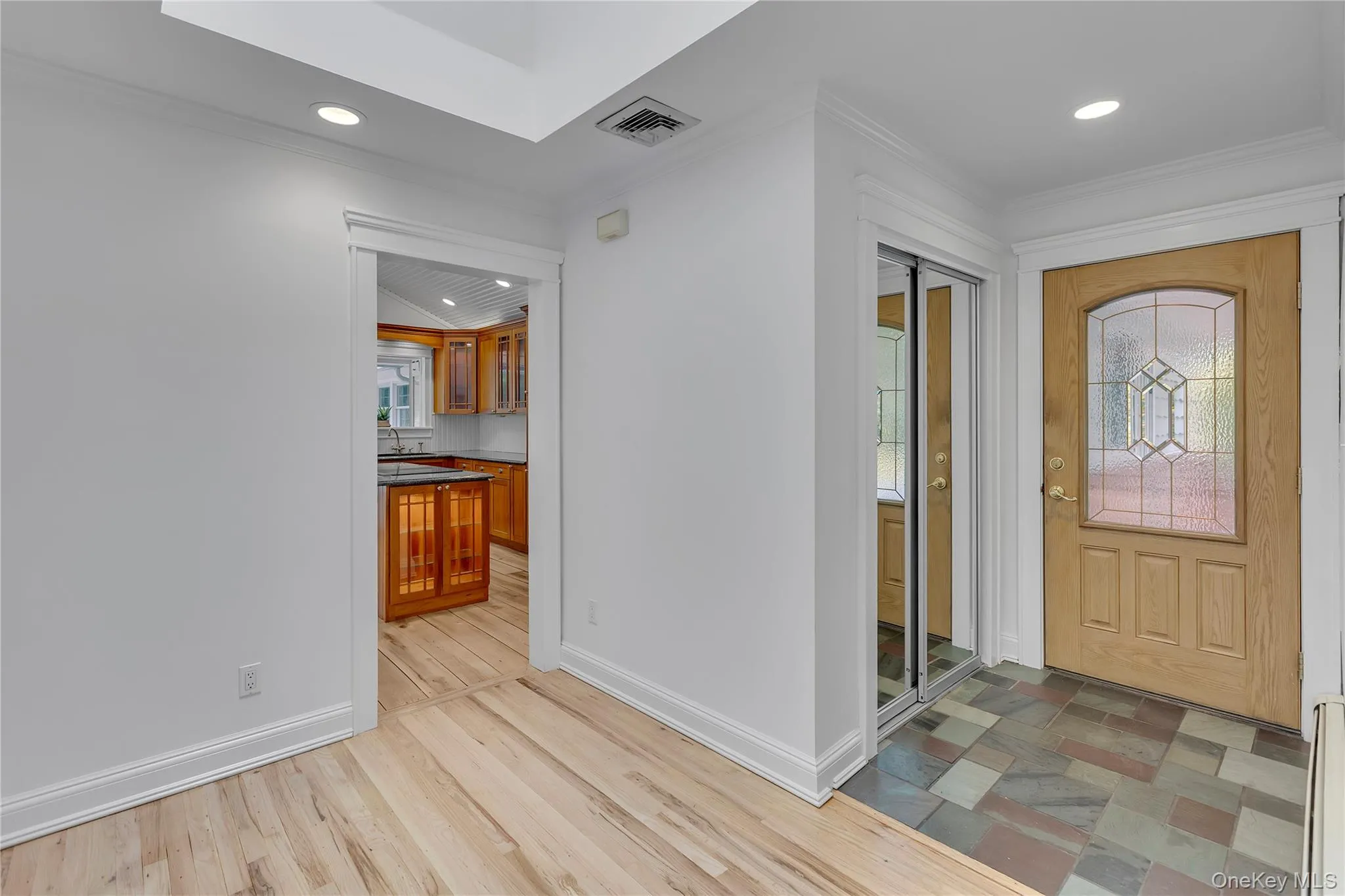 Entryway featuring a decorative glass front door, multi-toned slate tile flooring, and mirrored closet doors Entryway featuring a decorative glass front door, multi-toned slate tile flooring, and mirrored closet doors