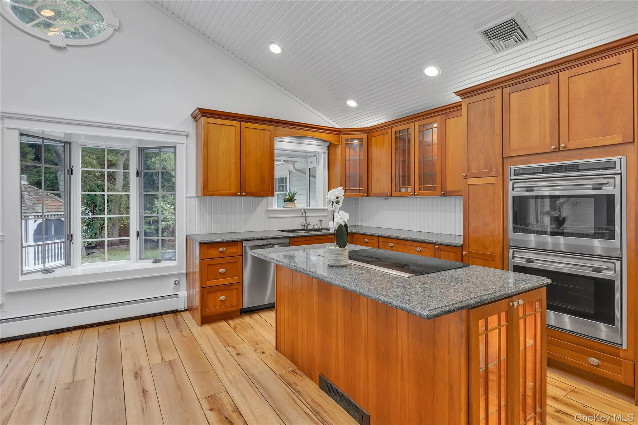 Kitchen featuring wood-finish flooring, vaulted beadboard ceiling, and light wood cabinetry Kitchen featuring wood-finish flooring, vaulted beadboard ceiling, and light wood cabinetry