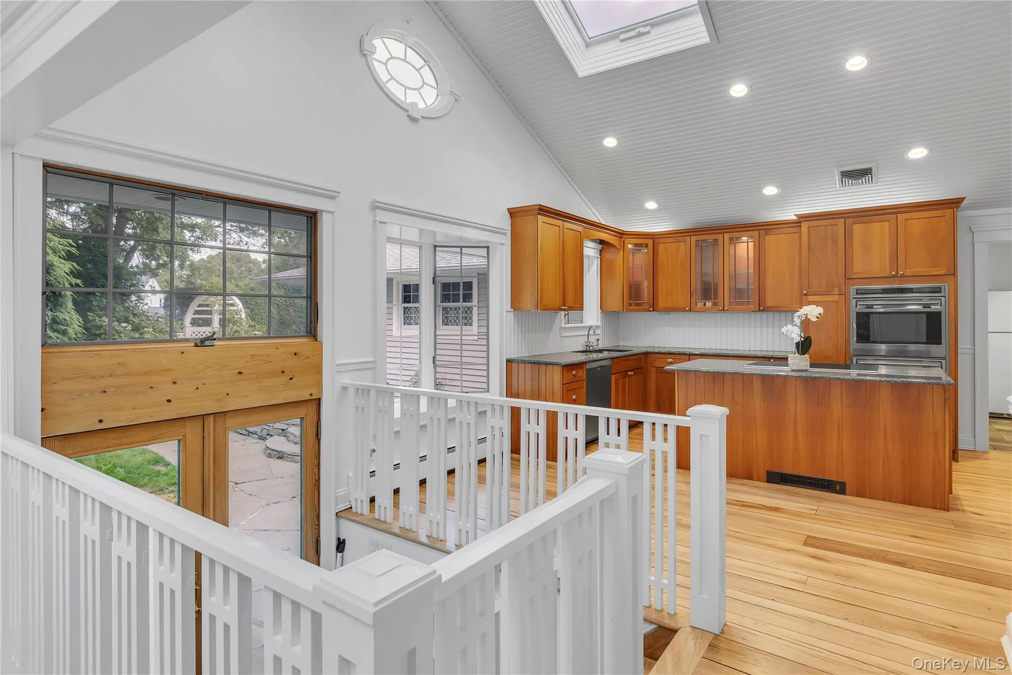 Kitchen featuring wood cabinetry, stainless steel appliances, and a skylight Kitchen featuring wood cabinetry, stainless steel appliances, and a skylight