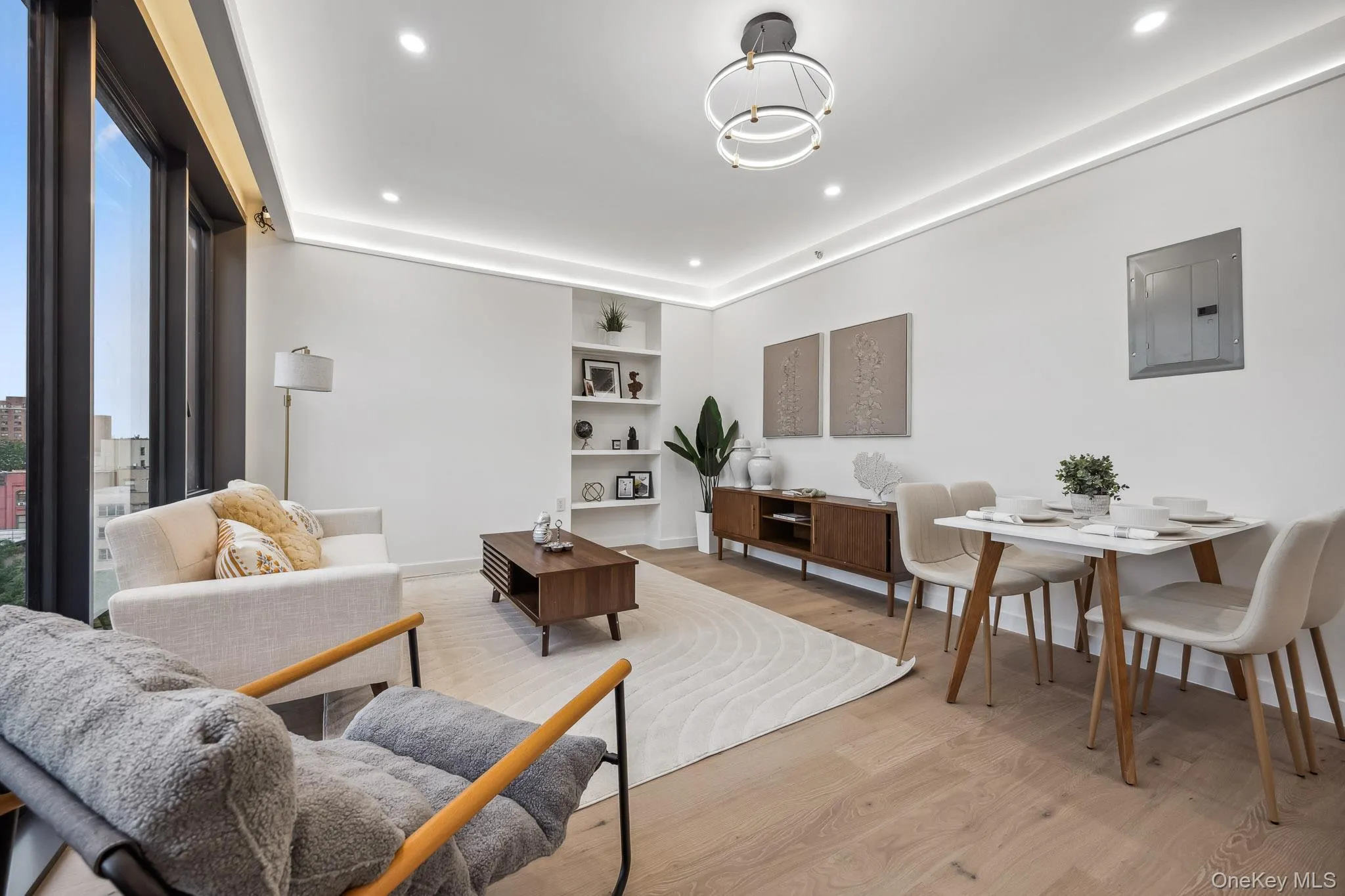 Living room with electric panel, light wood-type flooring, recessed lighting, baseboards, and built in shelves Living room with electric panel, light wood-type flooring, recessed lighting, baseboards, and built in shelves